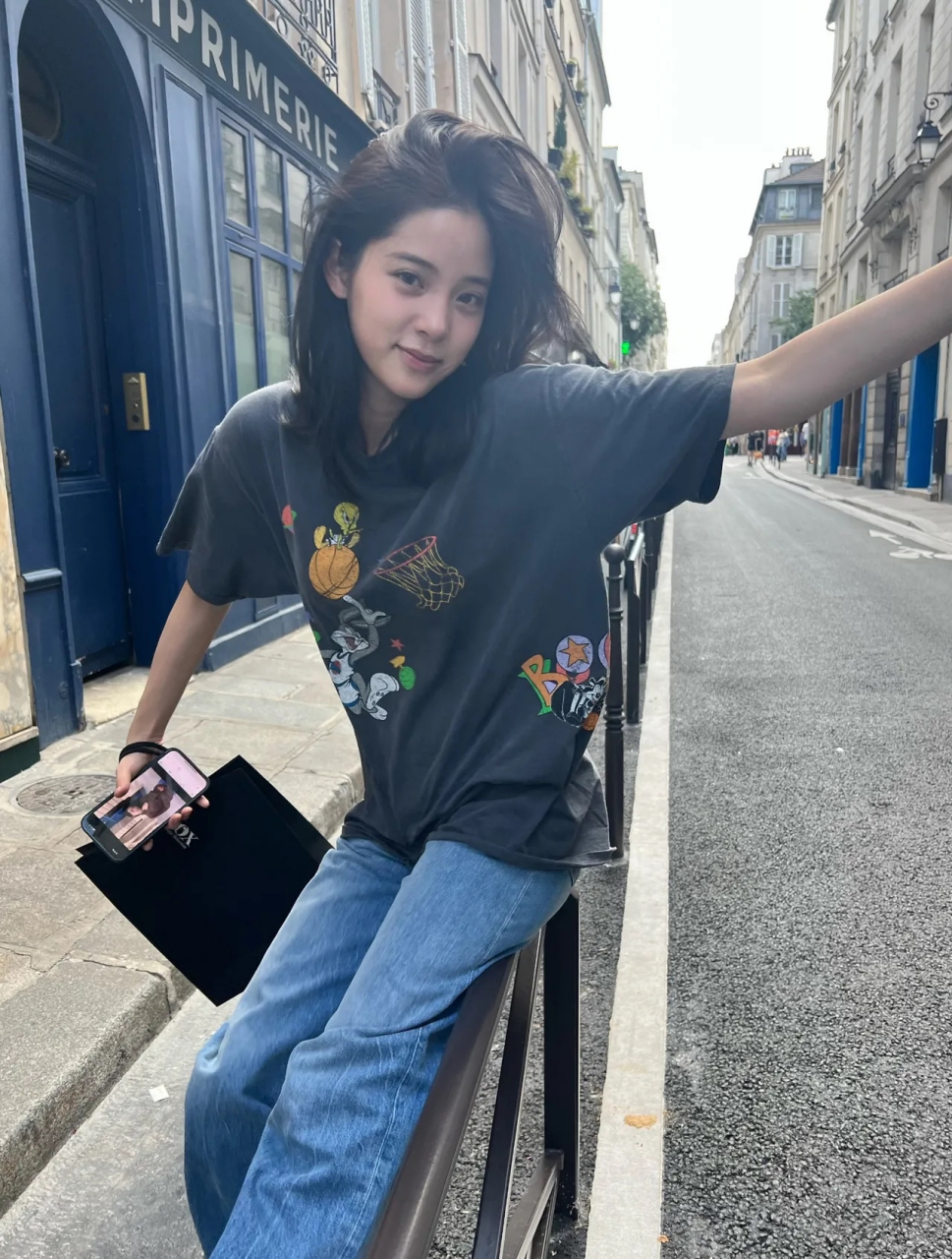 欧阳娜娜街拍,她穿了一深灰色的圆领短袖t恤,搭配一条蓝色的牛仔直筒