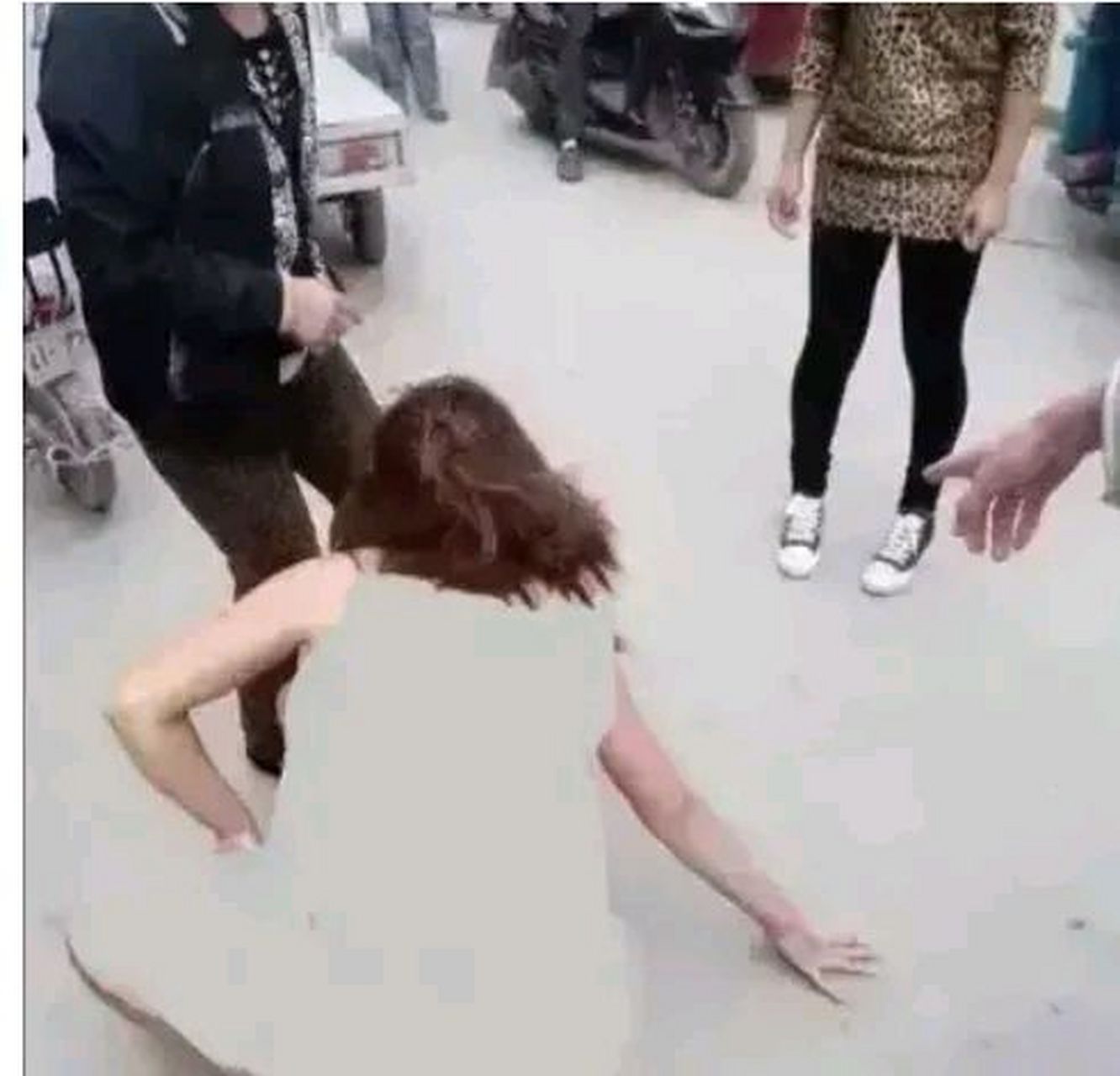 一个年轻女子在大马路上,被几个人扒光衣服一丝不挂仰面就地而坐,周围