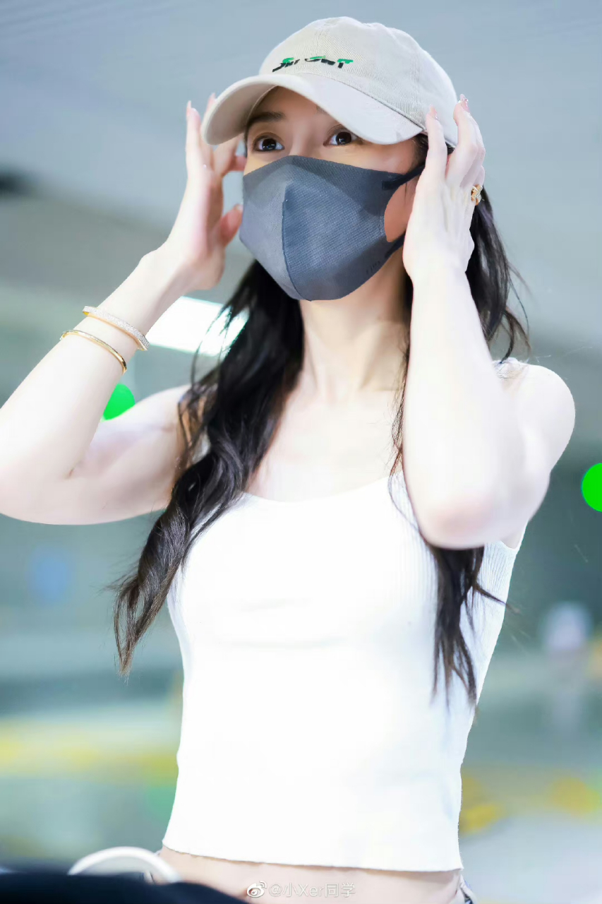 angelababy230626机场穿搭,白色背心搭配卡其色长裤与棒球帽,加以手镯