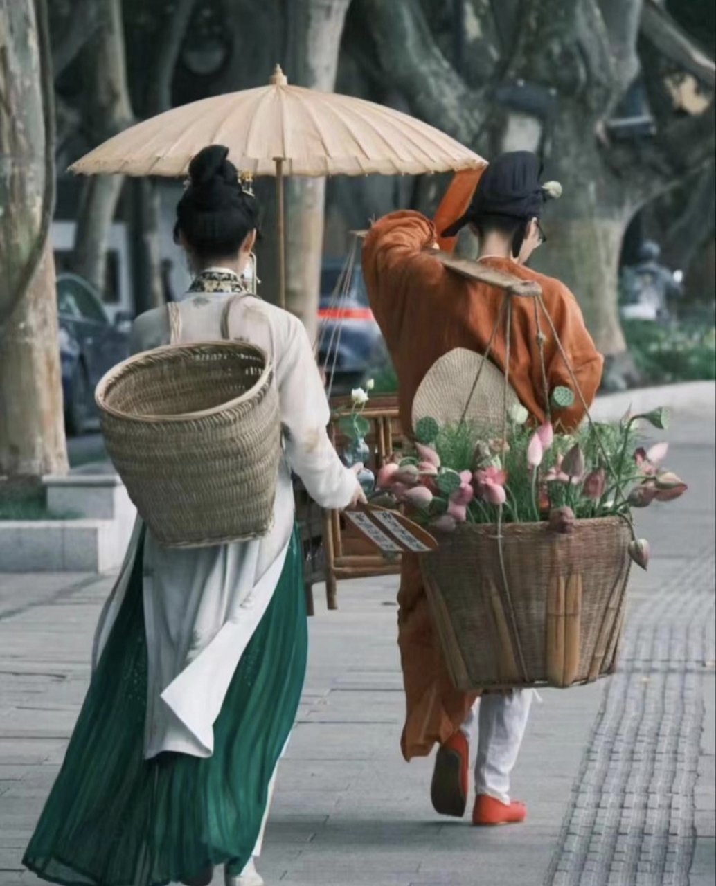 卖花郎挑个扁担,是唐时装扮,一头挑了一筐含苞待放的荷花,一头挑着