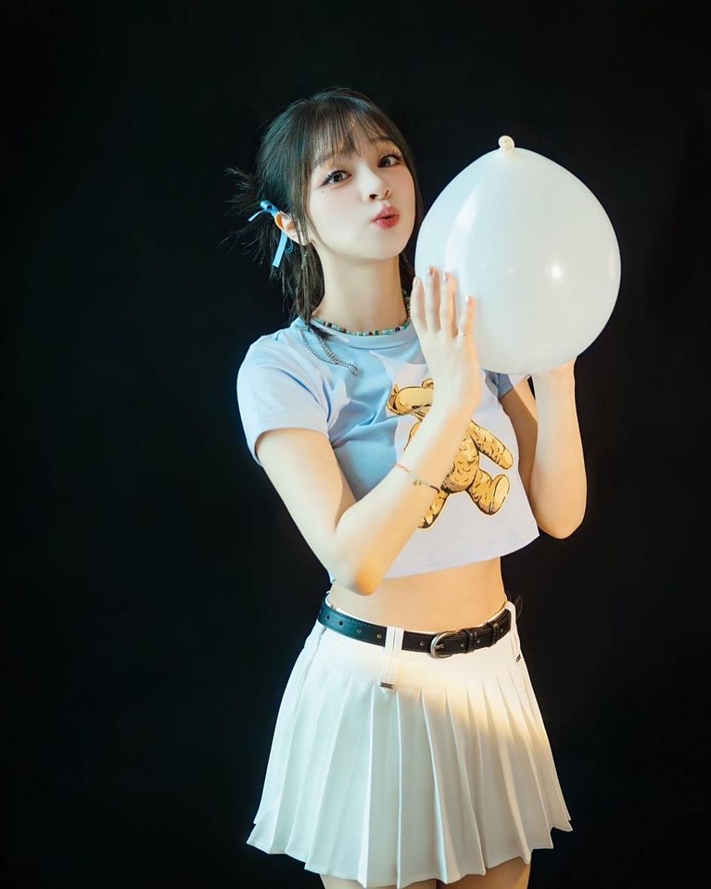 美依礼芽夏日氛围感写真照. 她身着露脐t恤,下身是百褶短裙.