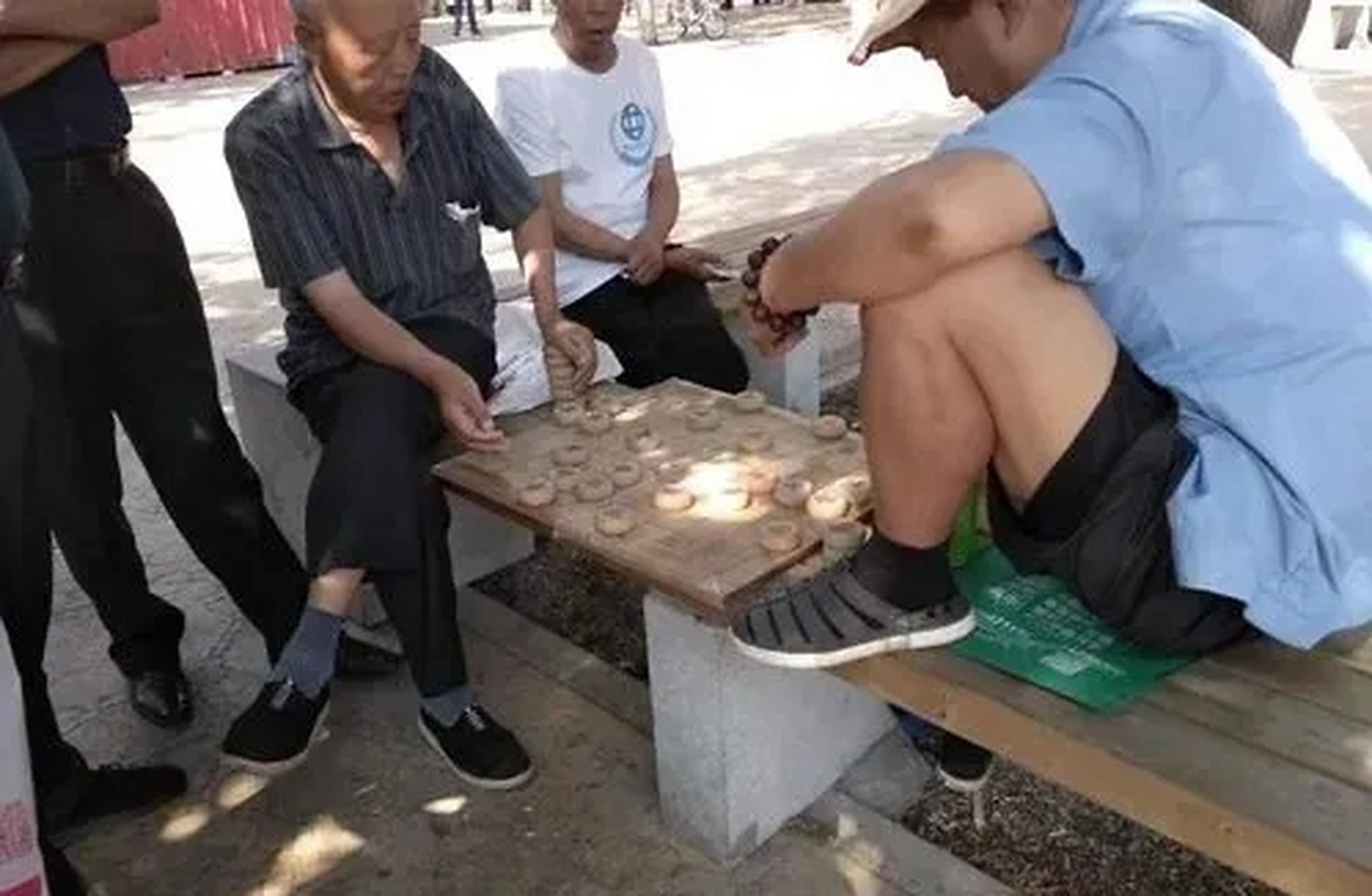 大爷在公园和朋友在下象棋,正在兴致勃勃的下着象棋,正在对朋友叫着