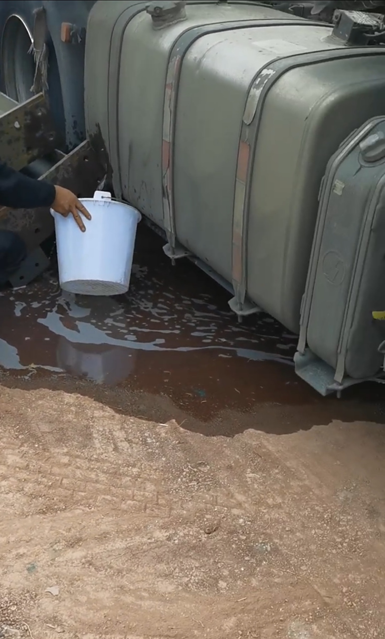 大货车油箱被磕到漏油了,小伙子拿了个白桶接油,我还说能接多少是多少