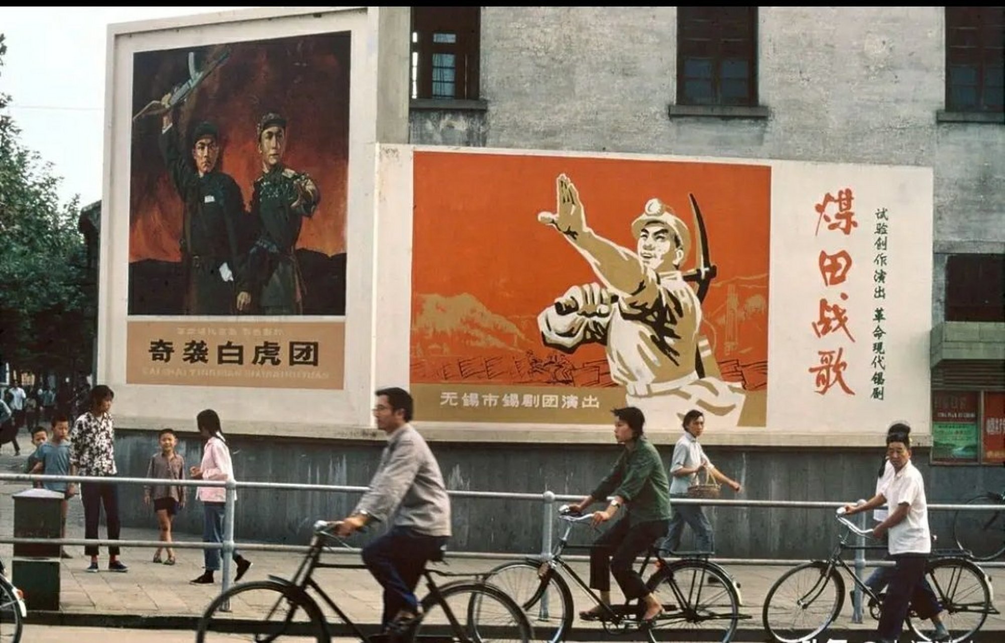骑自行车的行人和背景上有鲜明时代特色的宣传画.
