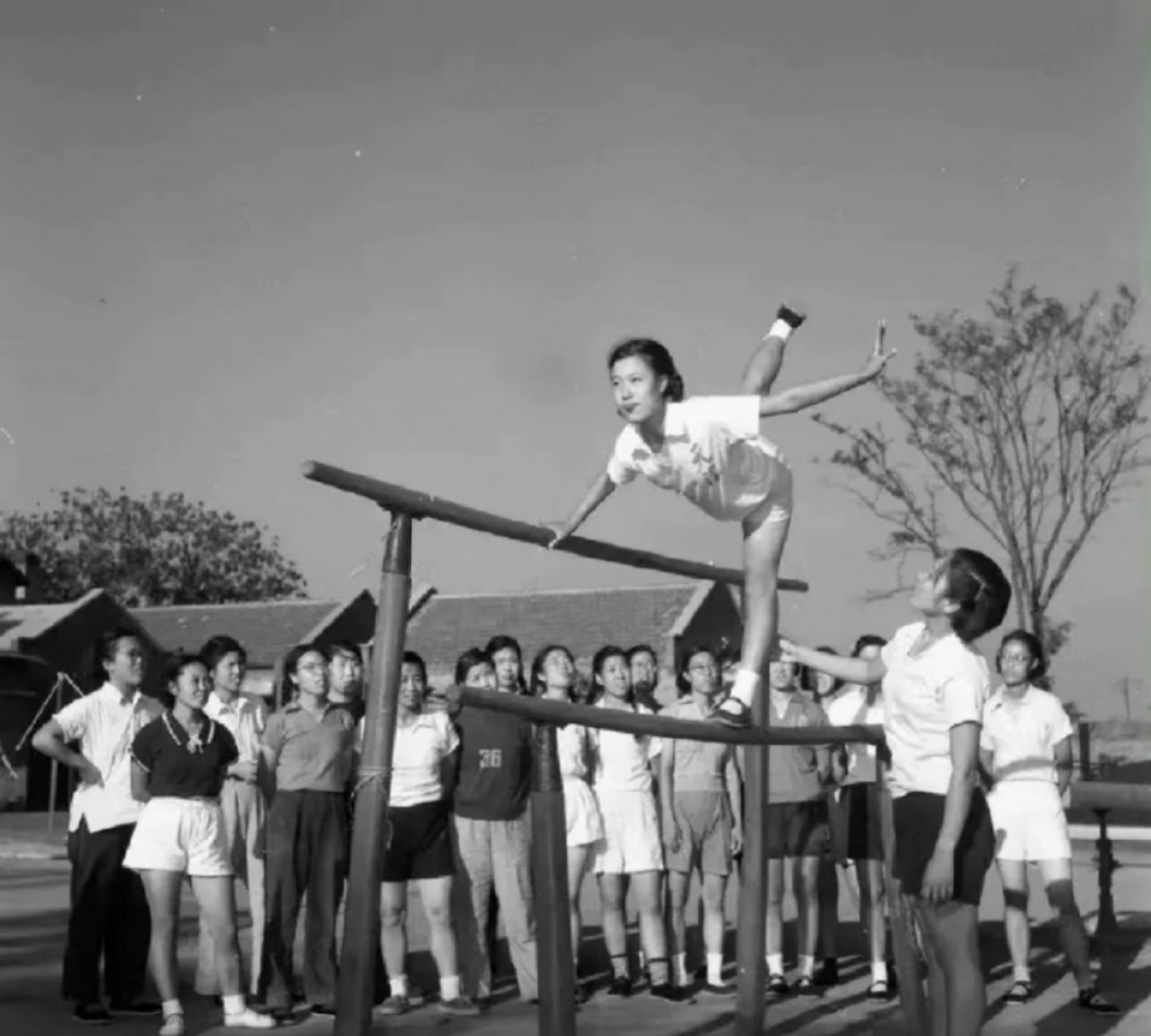 二十世纪五十年代,学校上体育课,女学生在玩双杠,只见她身轻如燕,现在