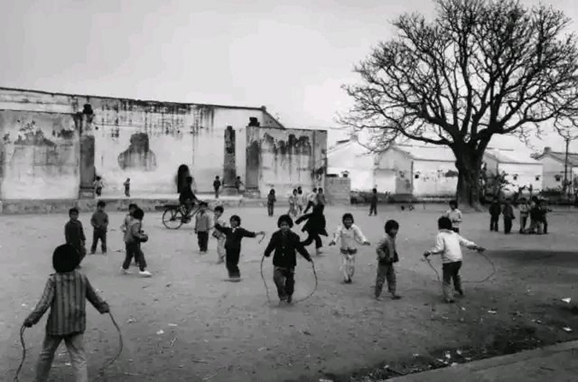 80年代一个小学的操场上,一群低年级小学生在上体育课,在操场上跳绳