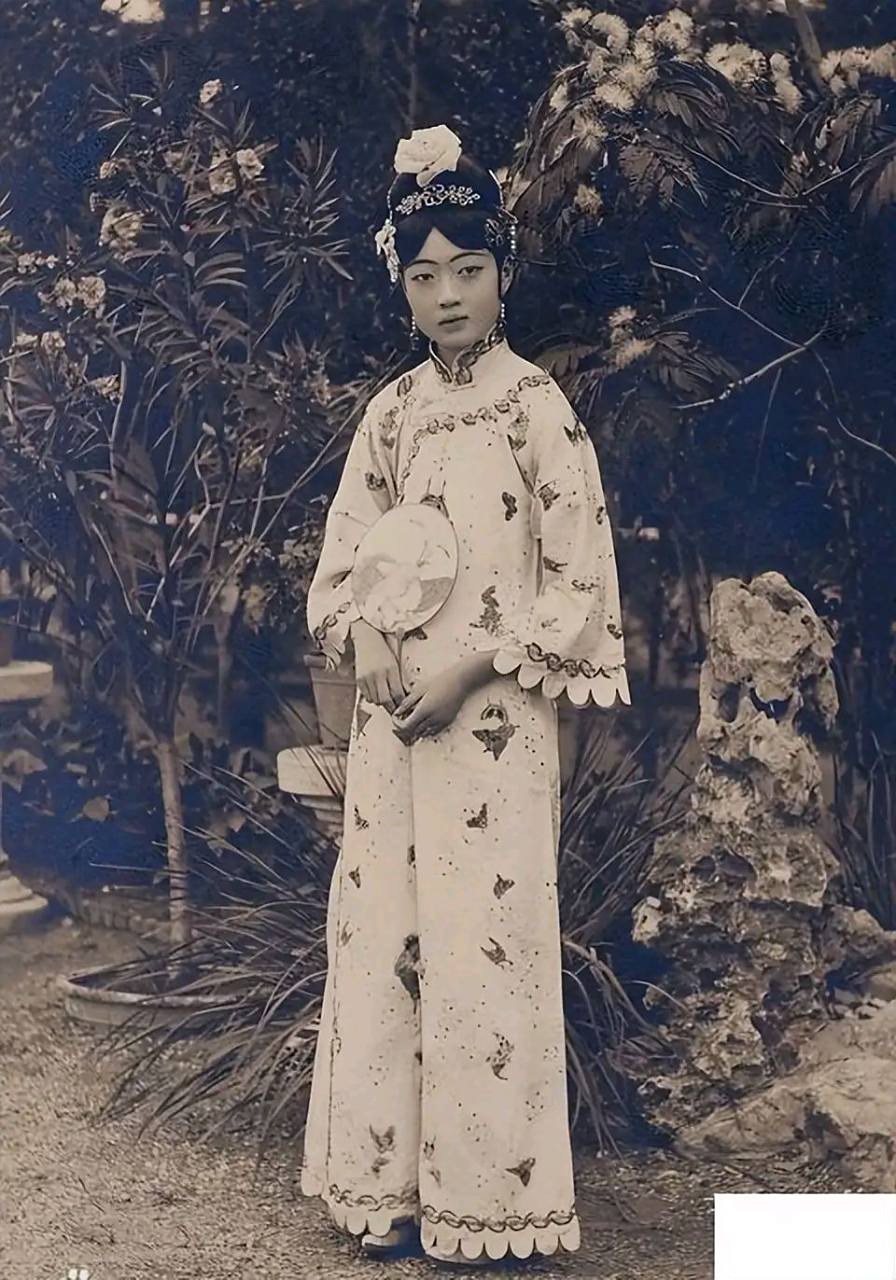 末代皇后婉容在庭院中的留影,照片中婉蓉穿着一件浅色印花旗袍,手中拿