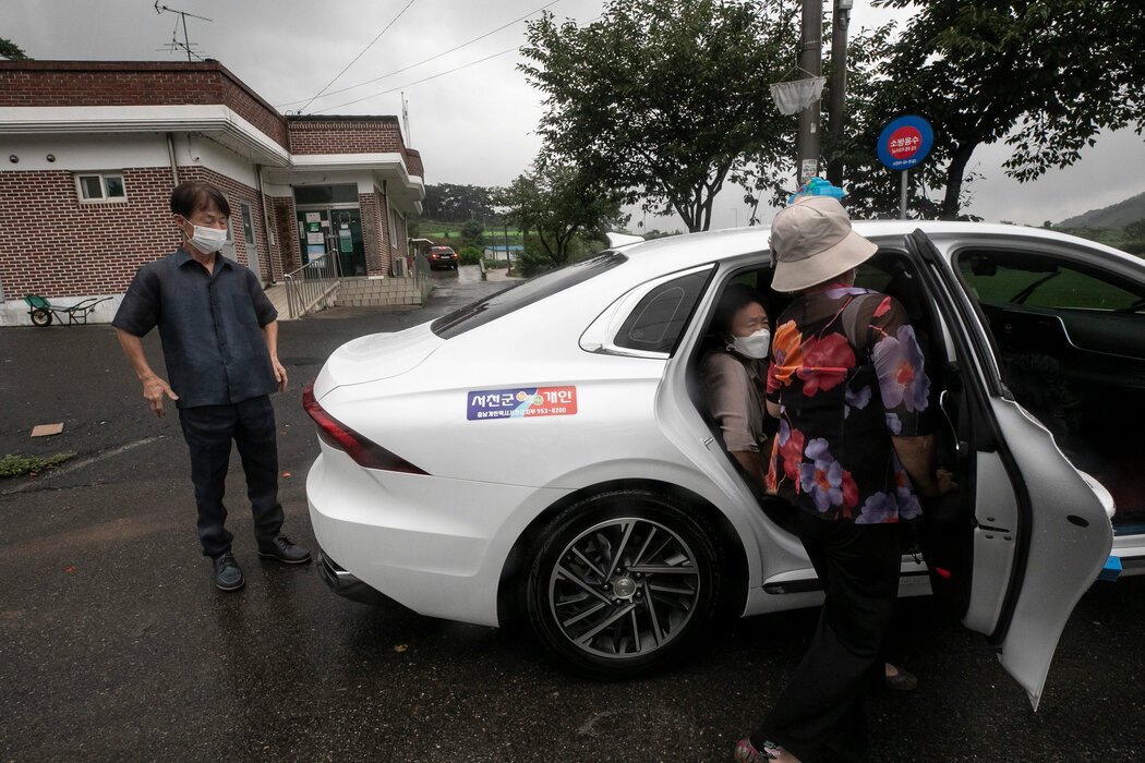 百元出租车司机李基业(左)表示:“我每周开两三次车载他们,比任何人都更了解这些老人。”