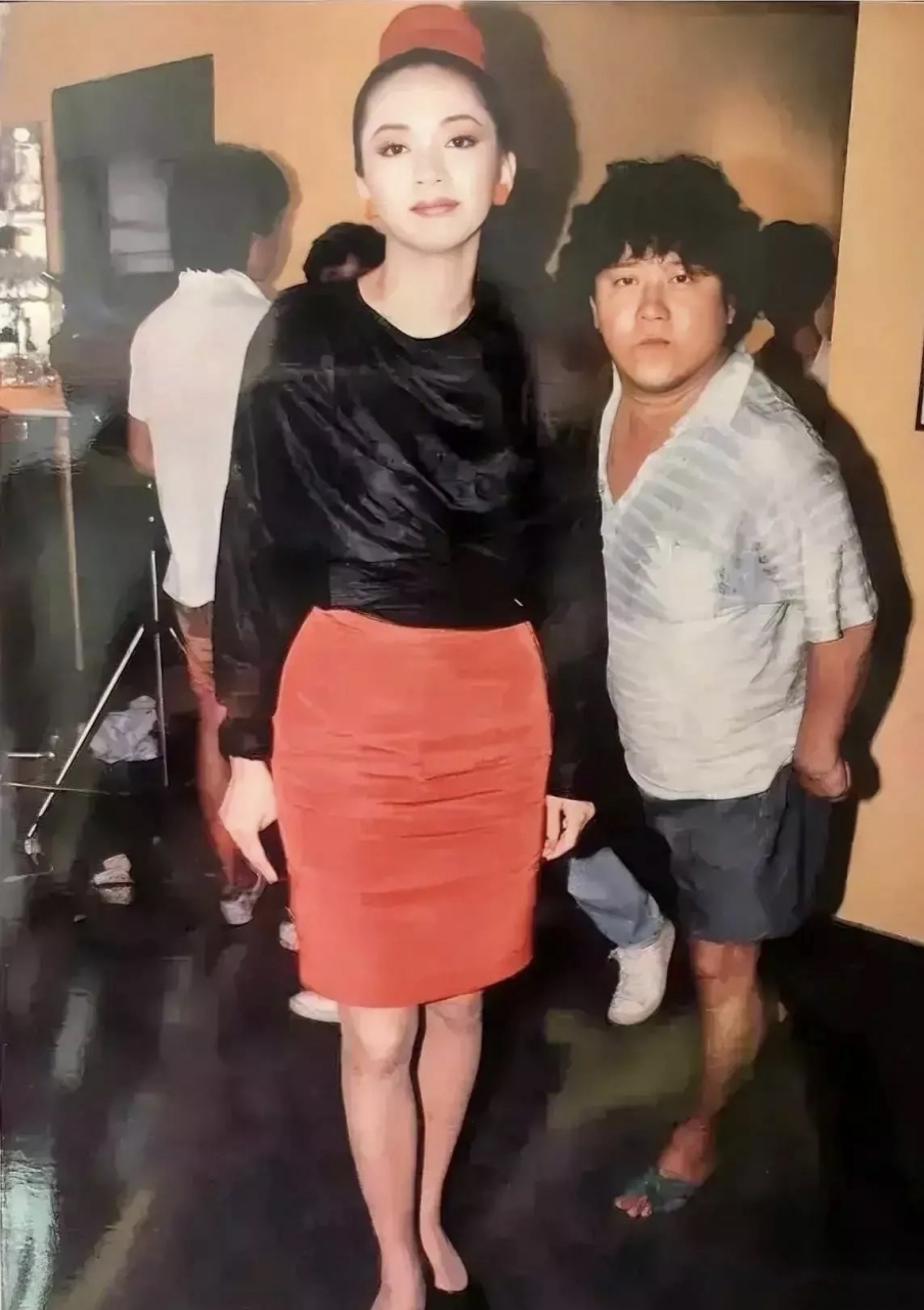 梅艳芳穿着黑色紧身上衣,搭配红色一步裙和黑色高跟鞋,一身打扮既漂亮