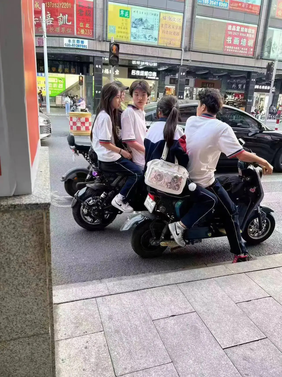 廣州街頭遇到兩名男學生騎著電動車,後座各自帶著一名女同學,真羨慕