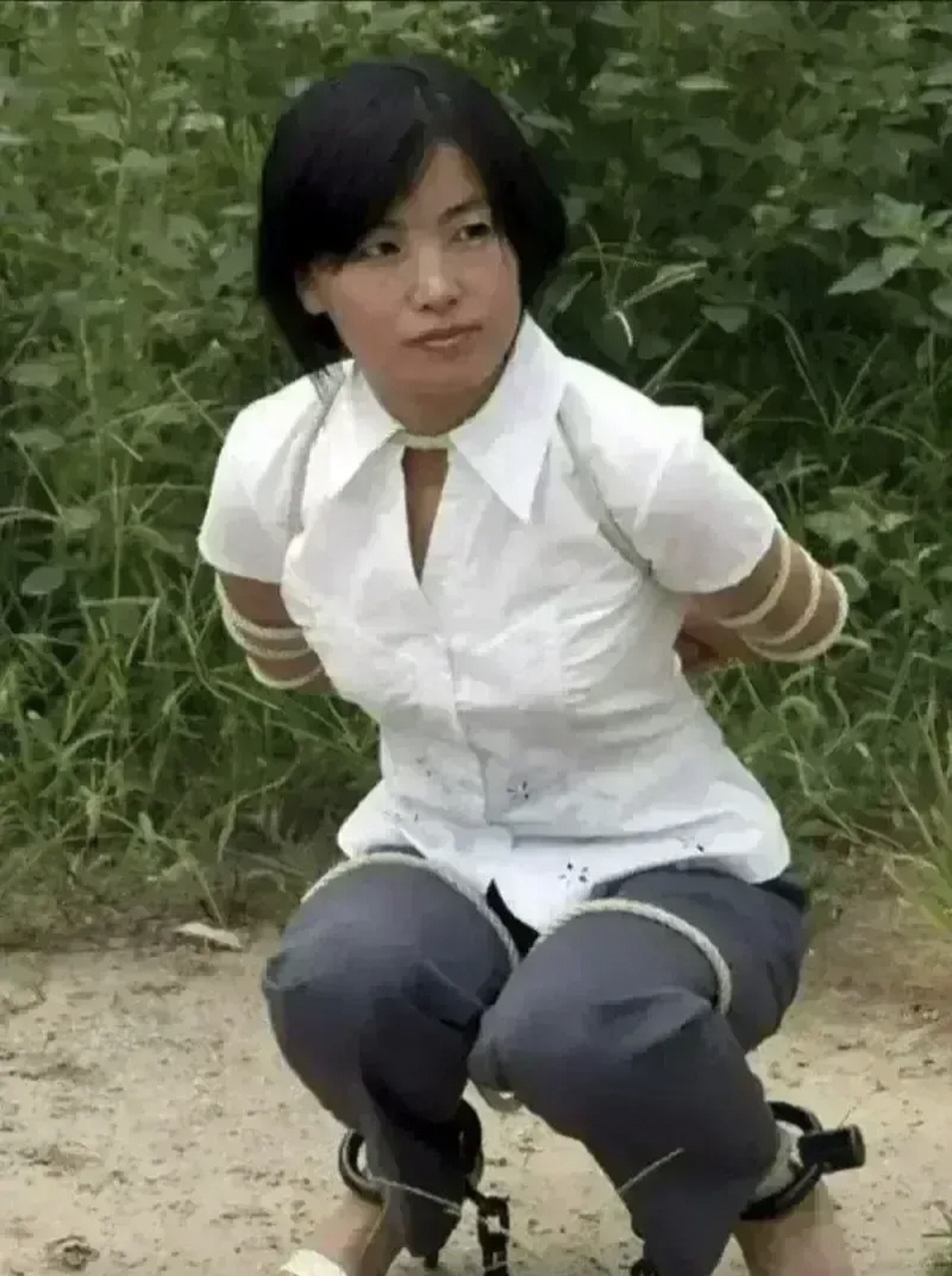 90年代,女犯人被执行枪决时的一张照片,她身穿白色衬衣,蹲在地上,被五