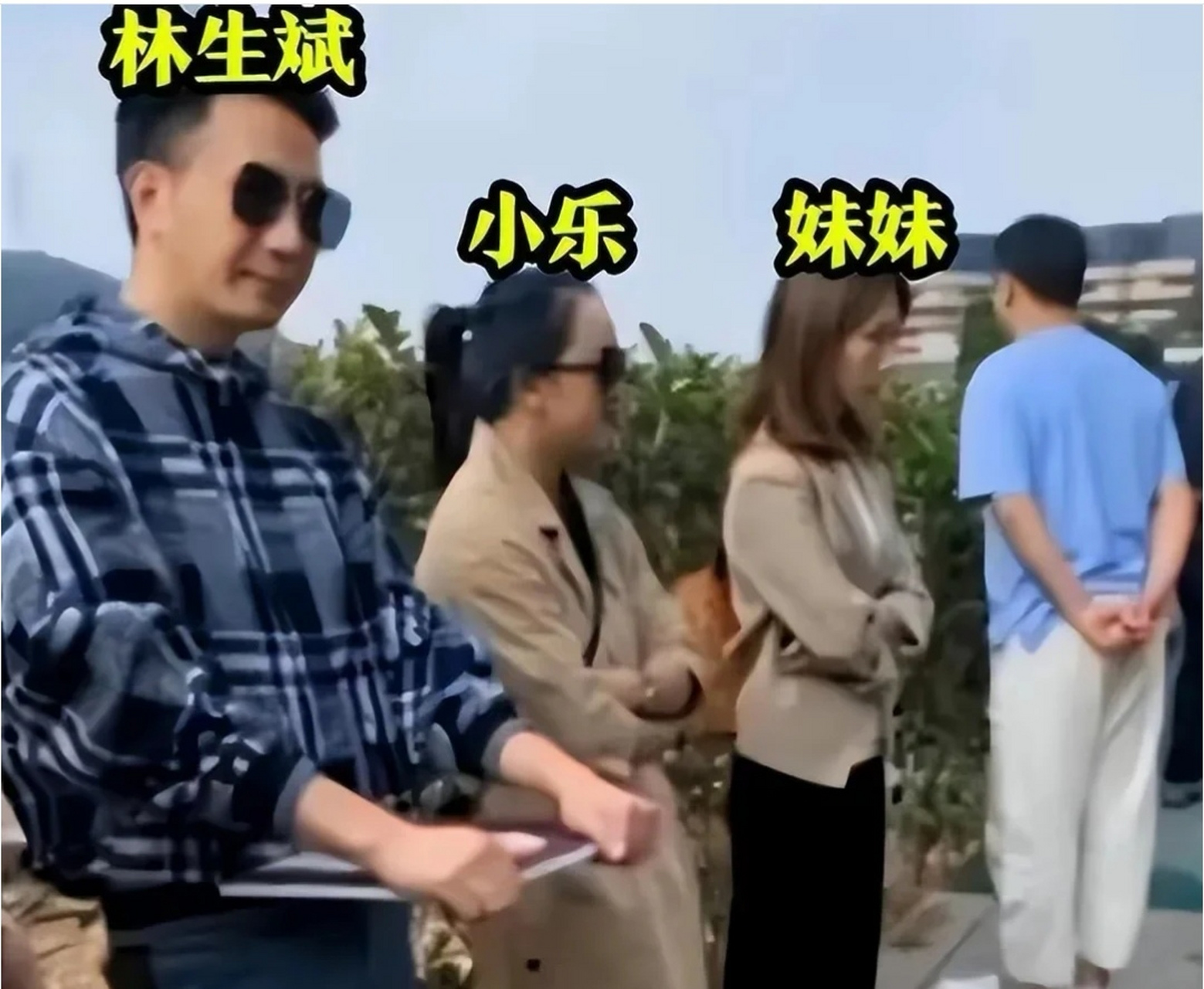 林生斌穿着格子衬衫,手上捧着朱小贞的遗照,戴着墨镜站在墓碑前