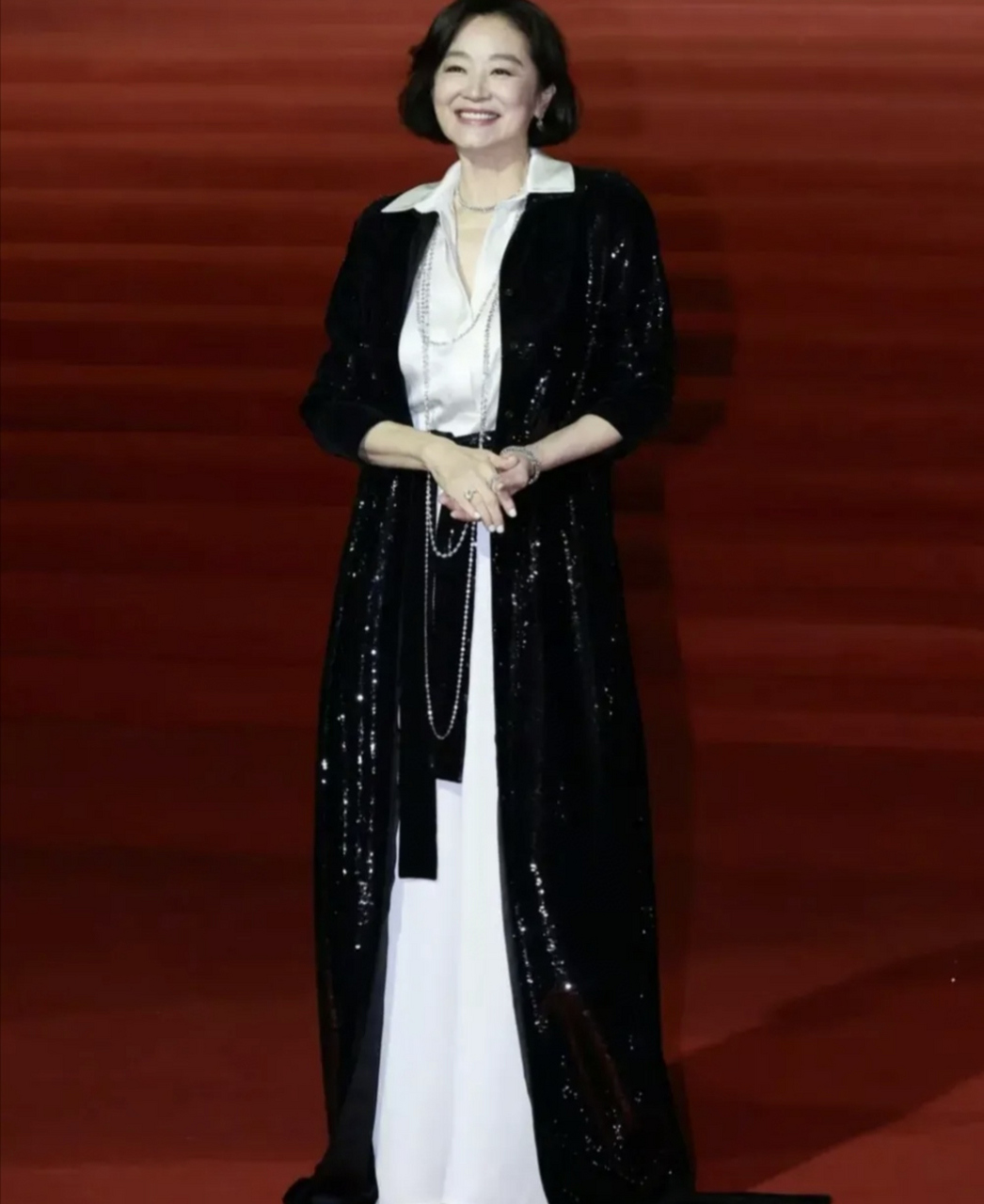 画面中,林青霞身着白色长裙,外披黑色拖地外套,展现出精致而高贵的