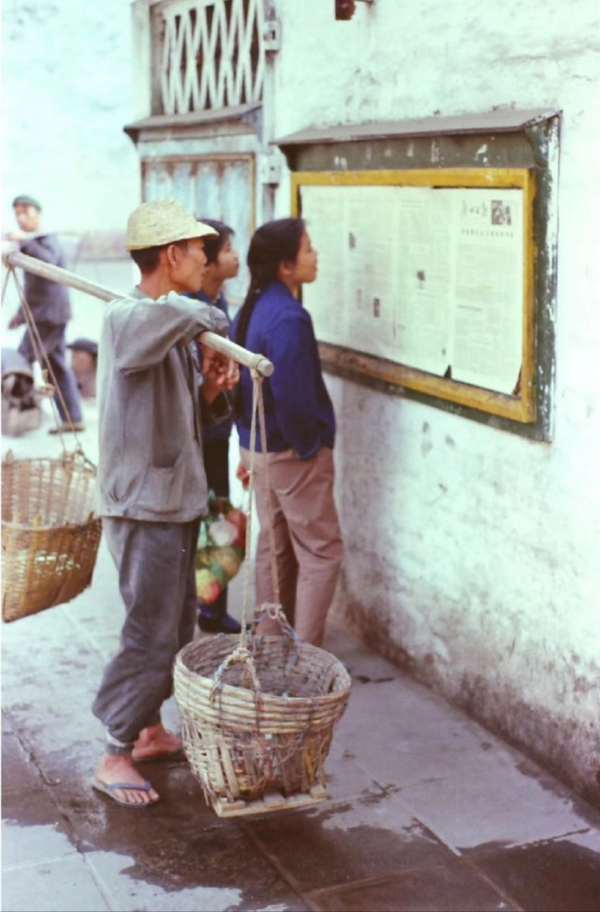 二十世纪八十年代,广州街头,工人们在看墙上的板报,他们边劳动边边