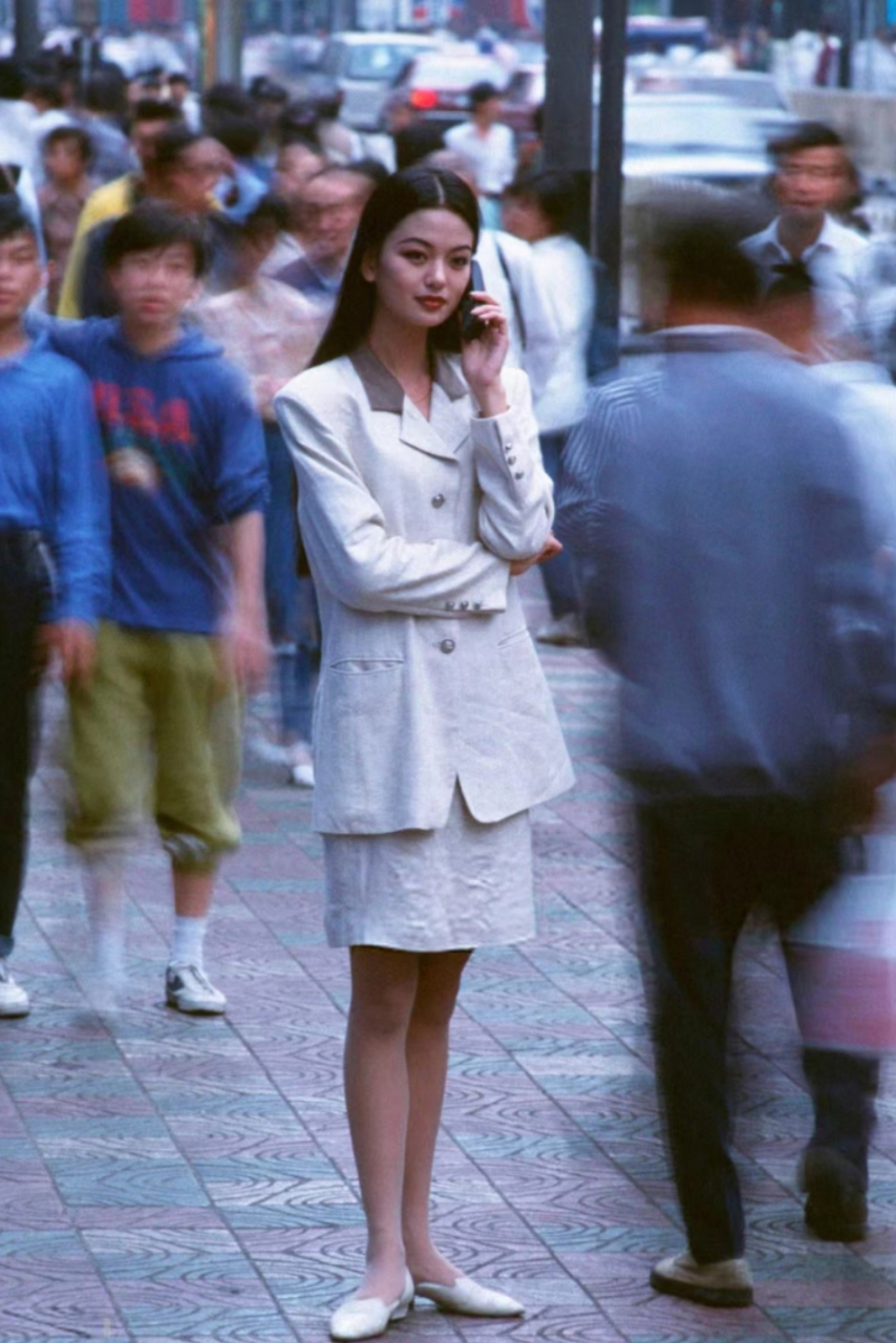 二十世纪九十年代,一位穿着时尚的女子站在街头打电话,那时候,电话