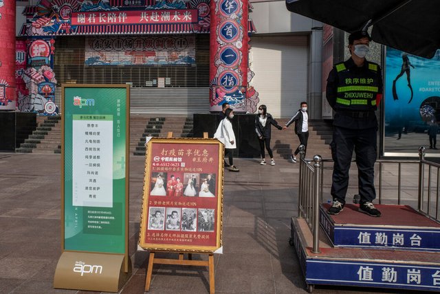 北京一个打疫苗享优惠布告牌边,一家国有照相馆打出了为接种新冠疫苗者拍婚纱照享九折优惠的广告。