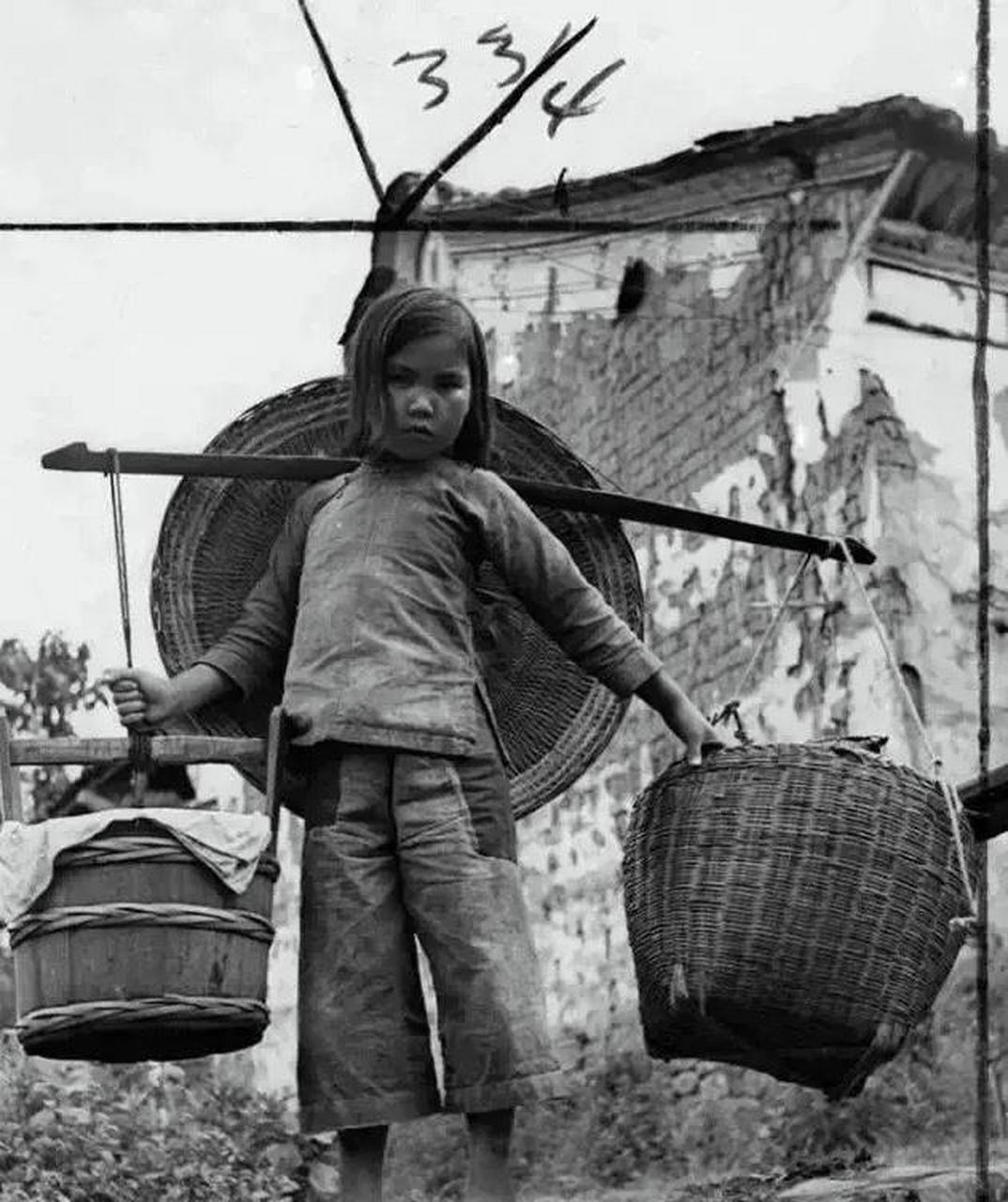 抗战时期的小女孩,她背着个比她身子还宽的斗笠,挑着担子,身上虽然是