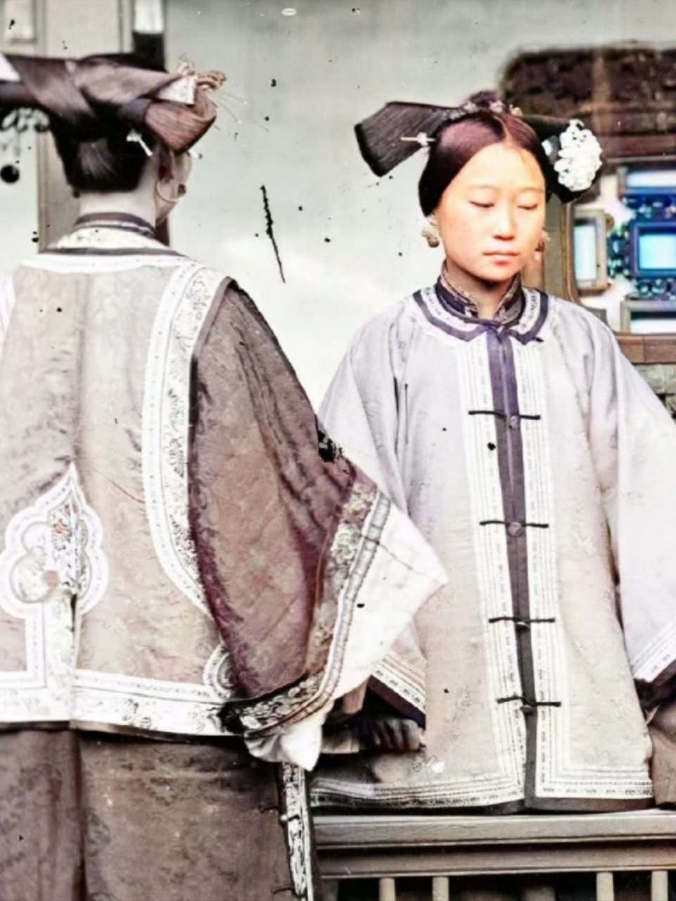 晚清时期,满族女子留影,她穿着满族传统长袍,头上梳着特殊的发髻,现在