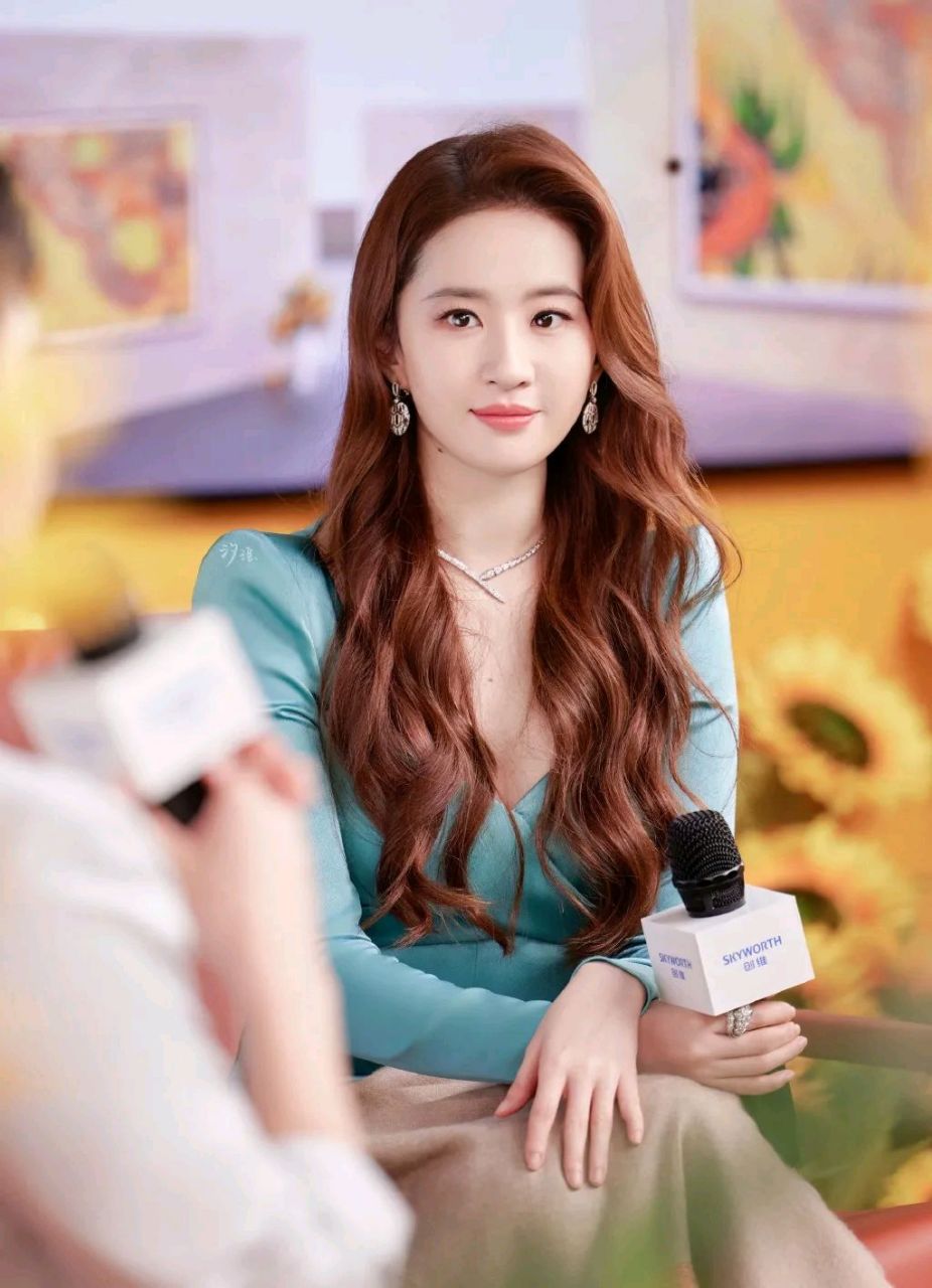 刘亦菲穿着水蓝色修身裙,还留着漂亮的大波浪卷长发,染着红色的嘴唇