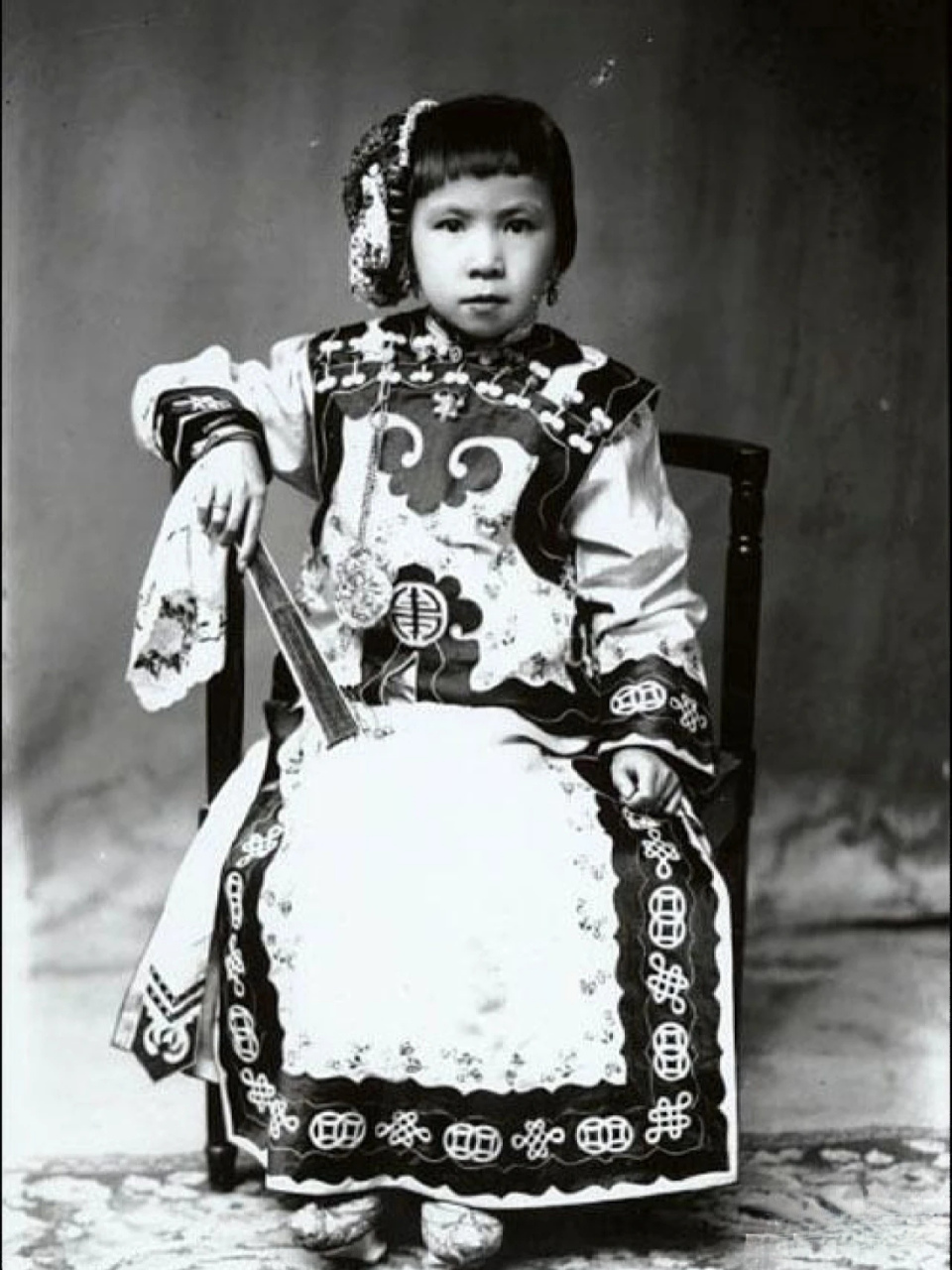 1895年,竖着蚌珠头的小女孩 看小女孩服饰华丽,发型精致,不知道是谁家
