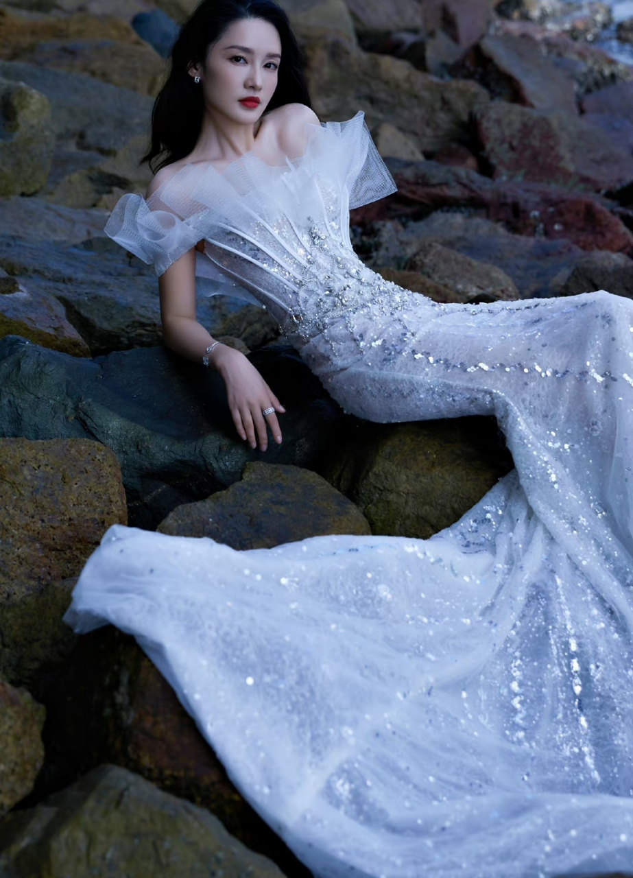 李沁在海岸边凹造型演绎现实版美人鱼,得体的亮片礼服,随着海风飘逸的