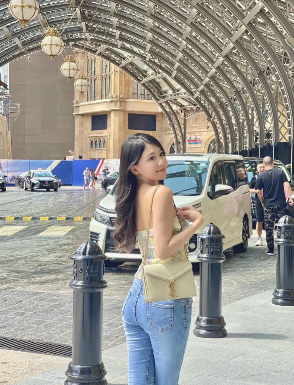 澳门街拍一位露肩花色上衣搭配经典蓝色紧身牛仔裤的长发美女,看起来