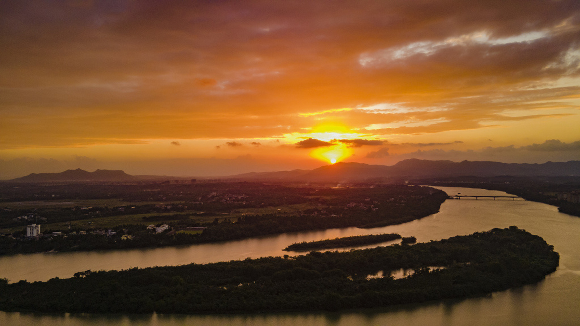 日暮时分,海南万泉河畔,太阳渐渐落下,将天边晕染成一片橘红,画面唯美