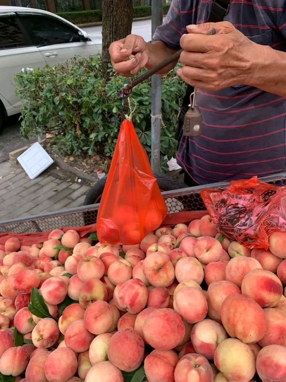 一大爷推着板车在路边卖桃子,遭旁边卖菜大妈抱怨,微信收款还有把收款