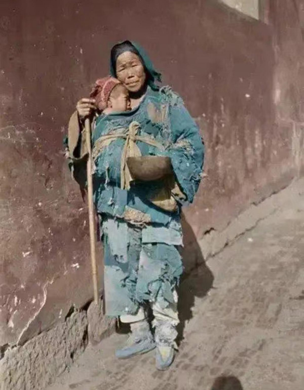 1917年,一位穿着破旧衣服的老妇人,拄着一根拐杖,手里拿着一个大碗,在