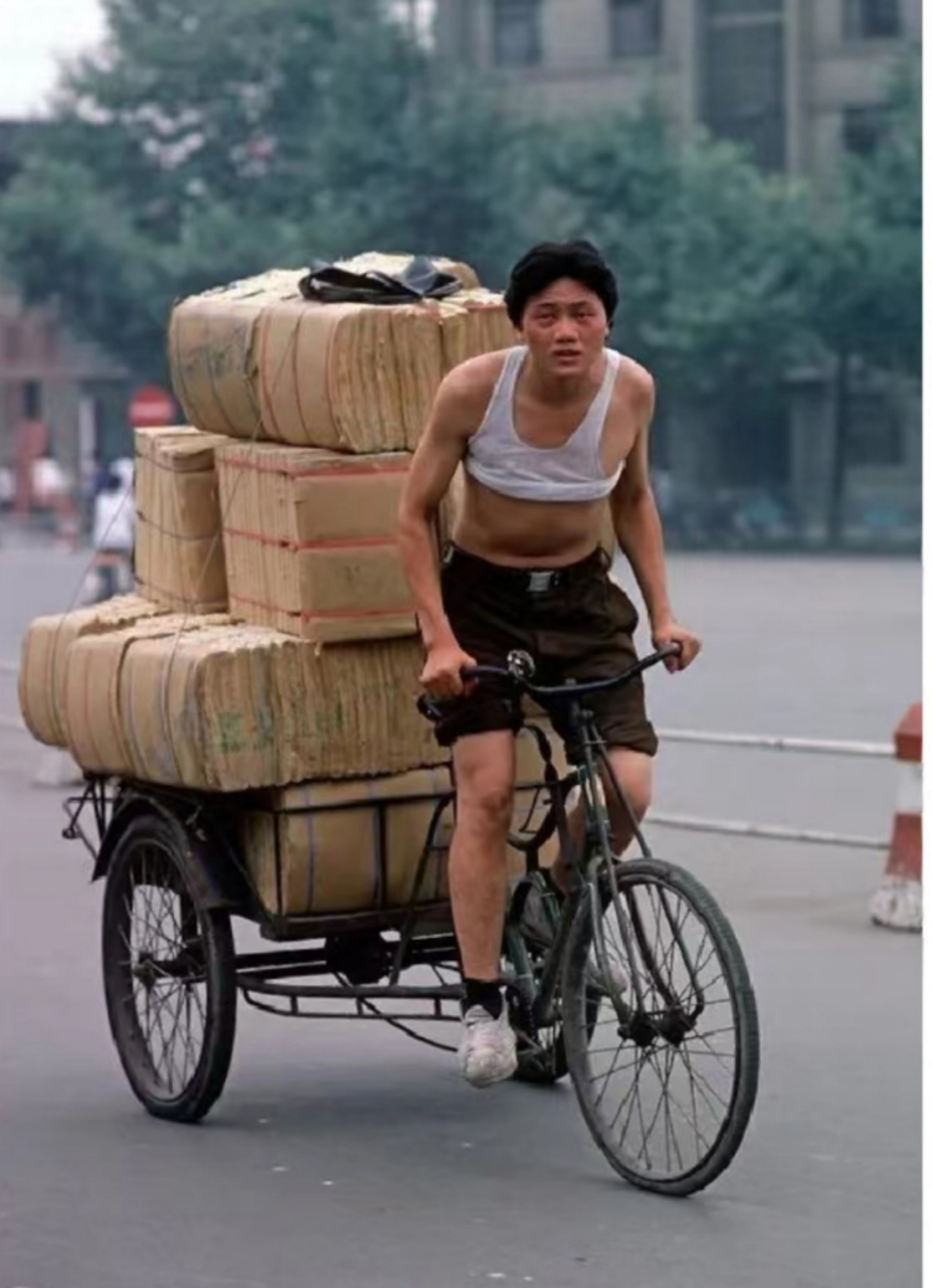1985年,成都街头,骑着人力三轮车拉着满载货物的年轻人!