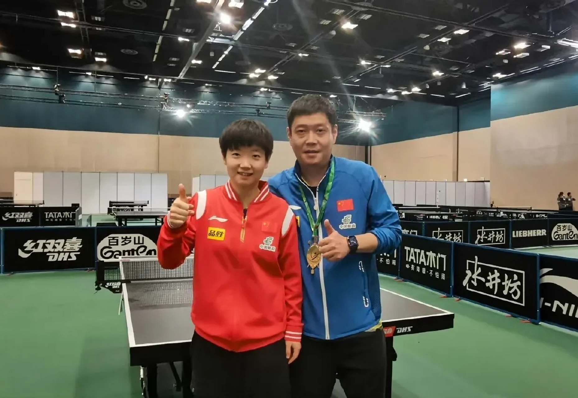 女单夺冠后,孙颖莎将金牌挂在师傅邱贻可的脖子上合影留念.