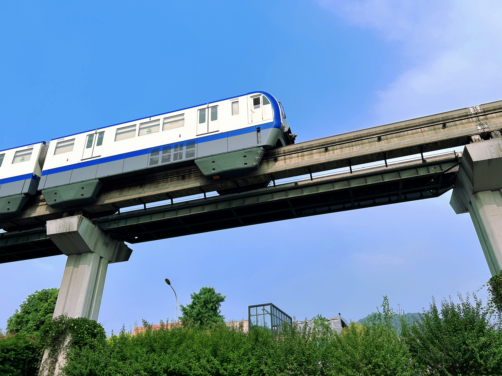 重庆轨道交通三号线,轻轨(单轨)列车在蓝天白云下穿梭而过.