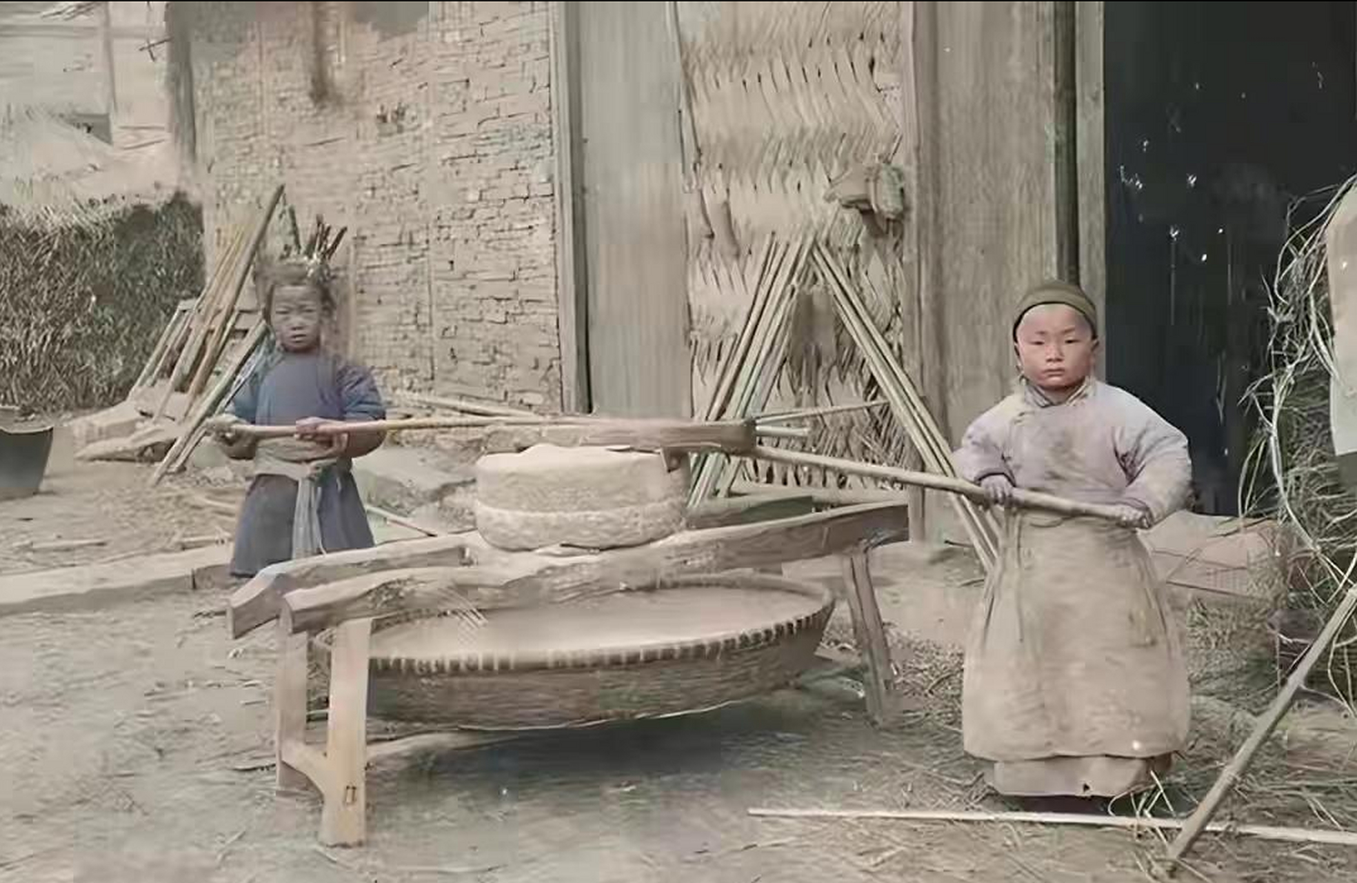两个看似只有四五岁的小孩正合力拉着石磨,在当时的环境下,穷人家的