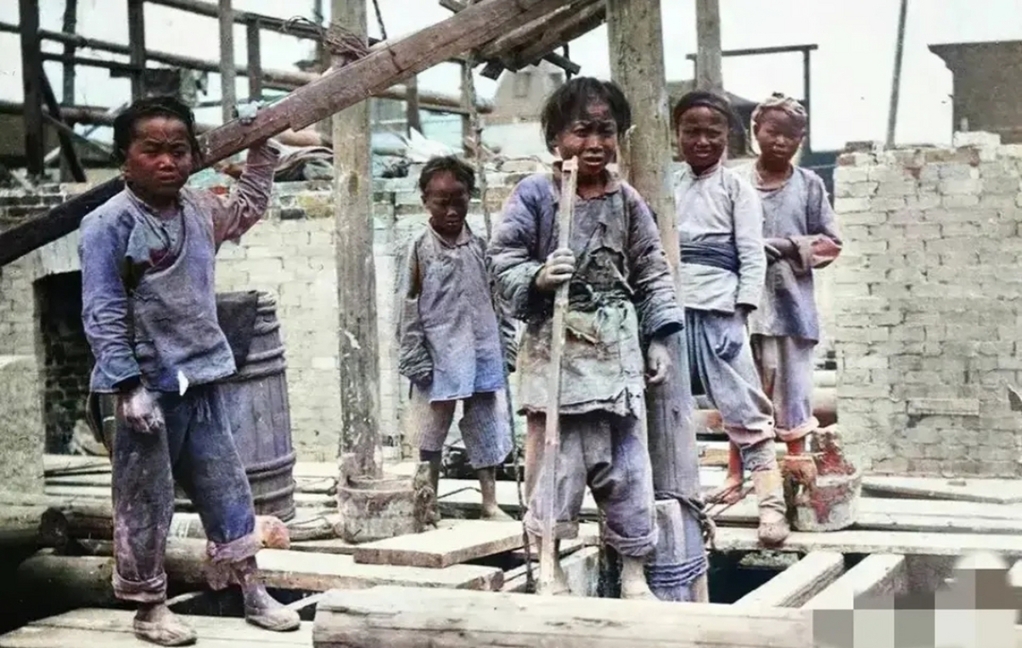 民国时期,建筑工地上,几名"童工"正在扛木料,他们的身上穿的破破烂烂