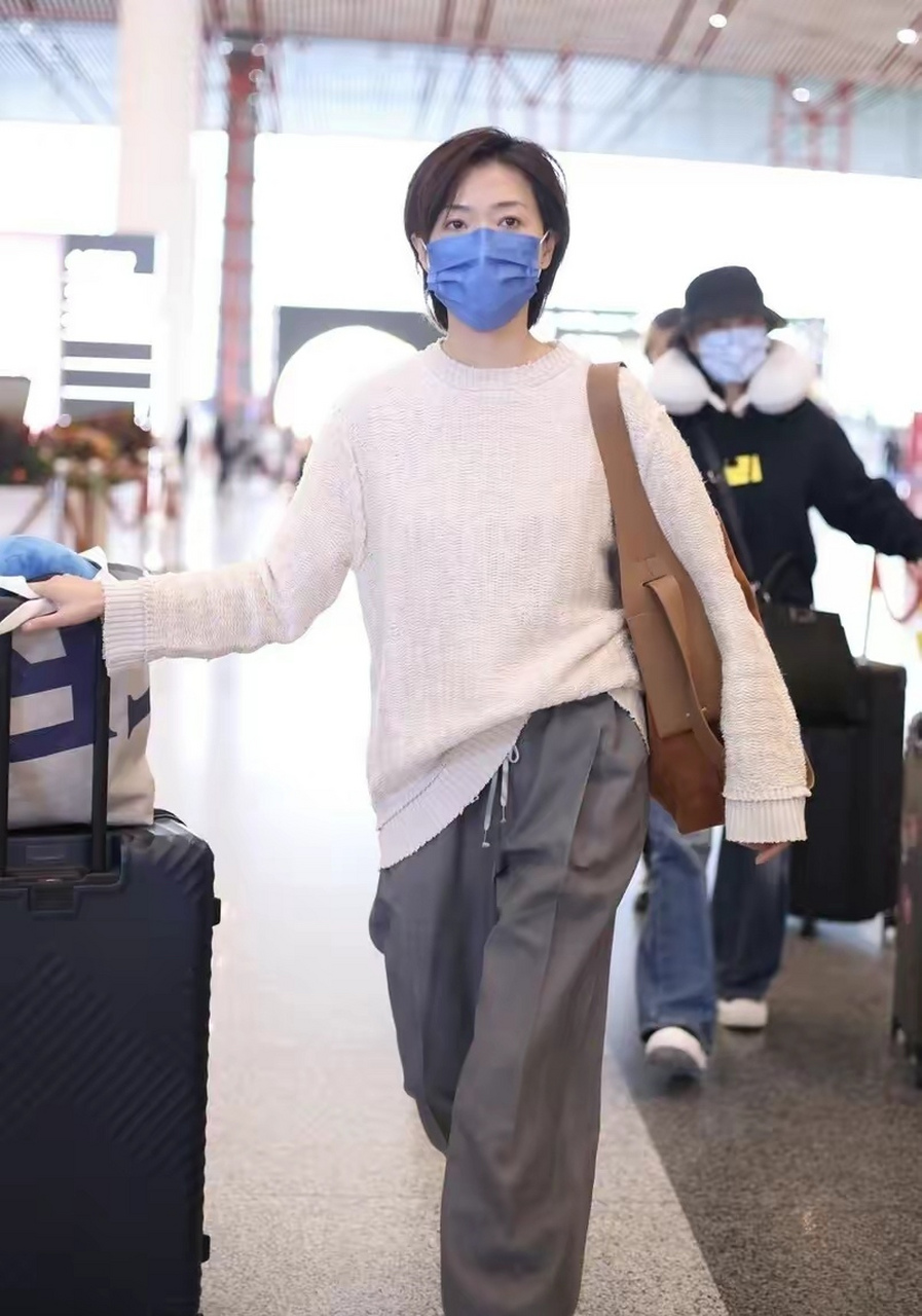 万茜北京机场街拍穿搭 身穿米白色针织衫,搭配灰色老爹西裤 肩上的