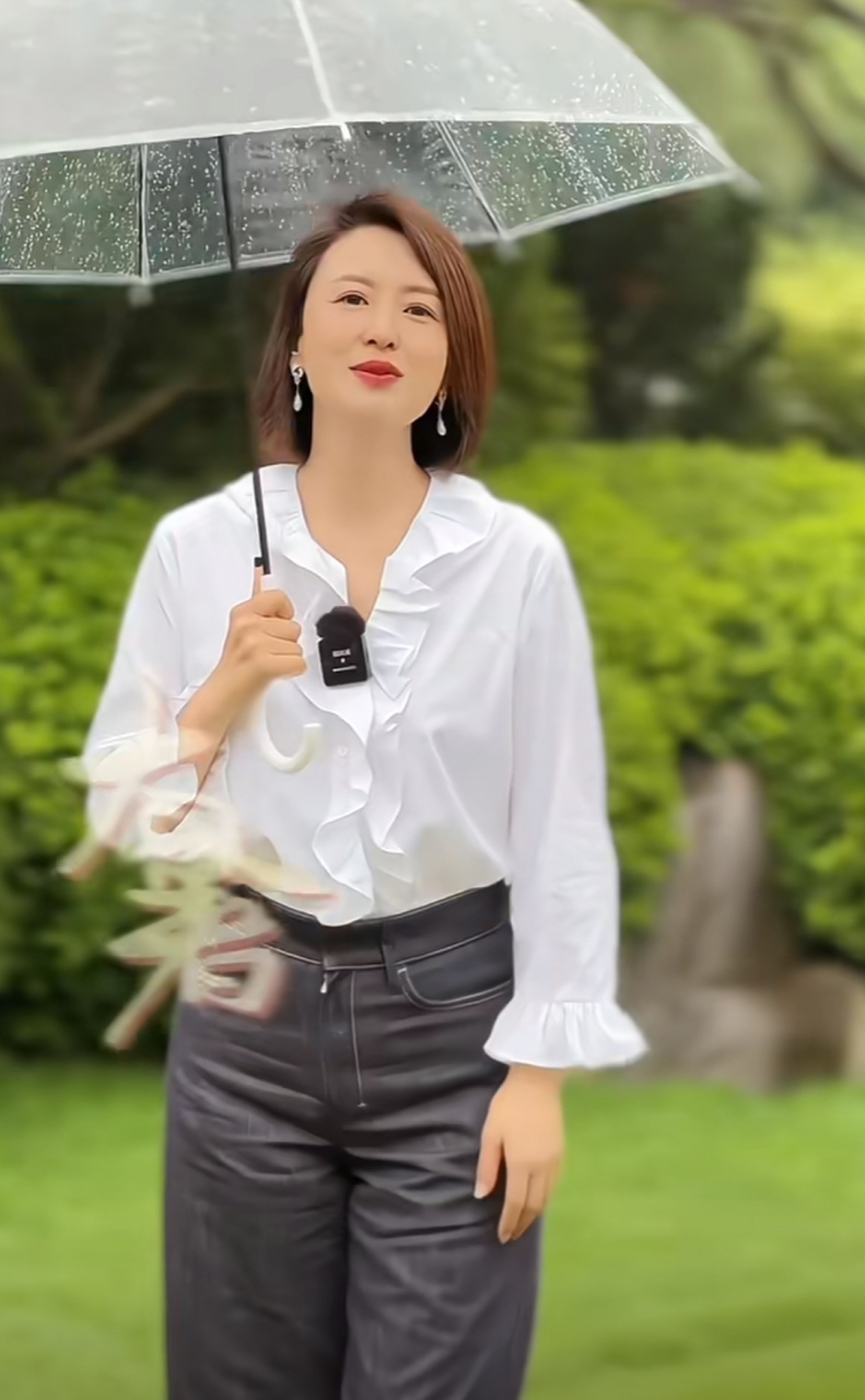 张蕾拍外景短片,为了节目效果特别撑了一把透明雨伞,配合她的白衬衫和