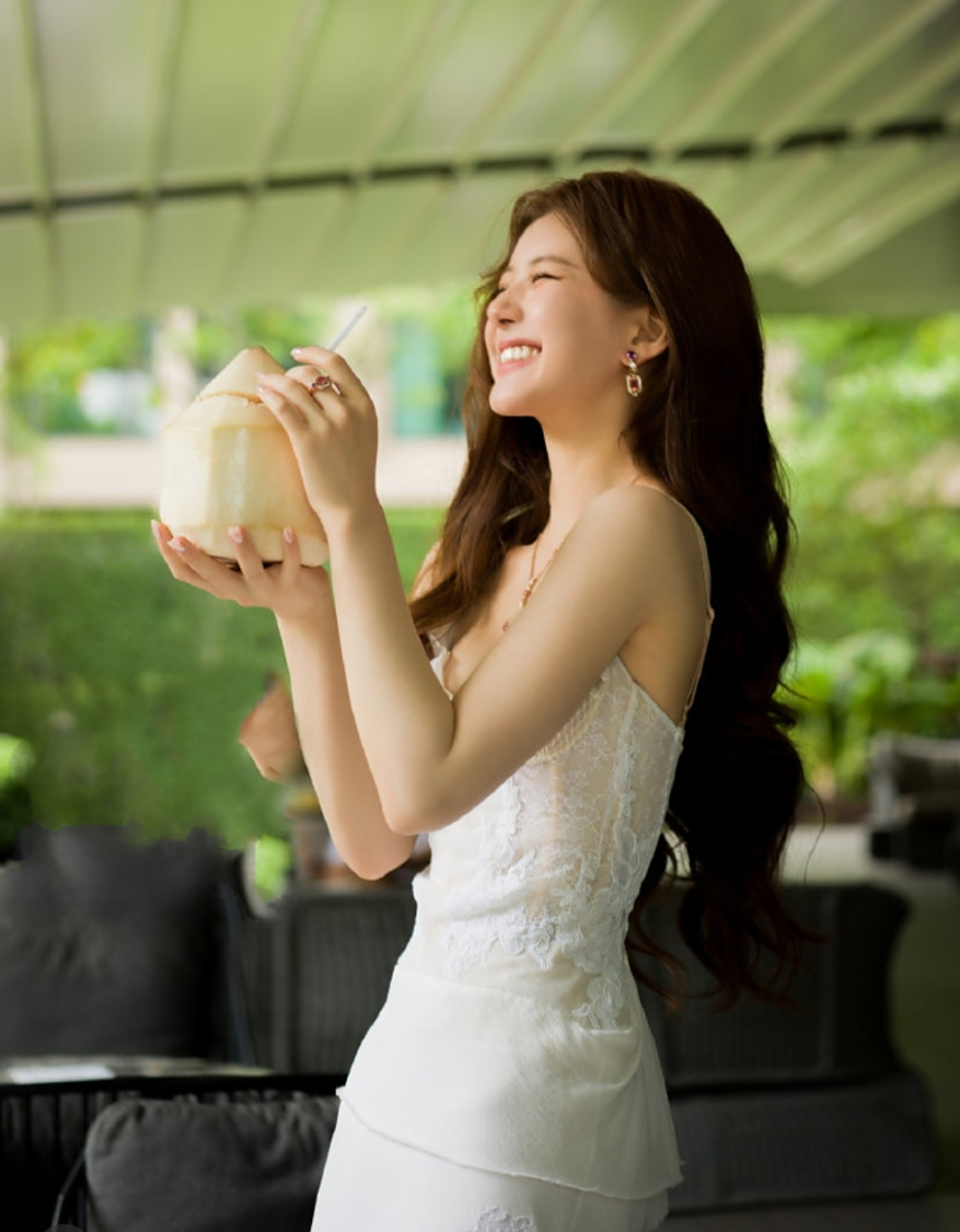 赵露思捧着椰子汁拍美照,卷发及腰高级感十足,白色礼服更添几分女神范