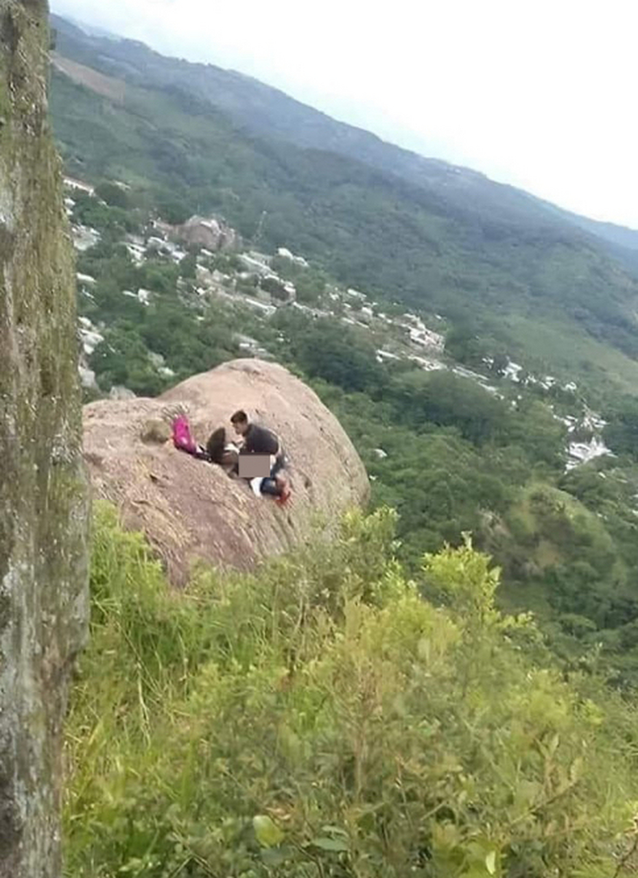 这是一张情侣在"崖边激战"的相片,相片中一对男女居然就在崖边巨石上