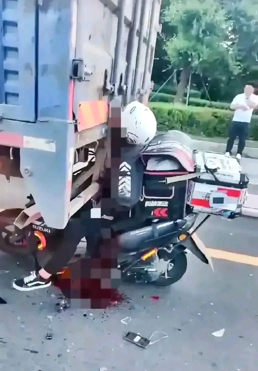 外卖小哥送餐途中,由于疏忽,直接撞上了卡车上,身体死死的卡住