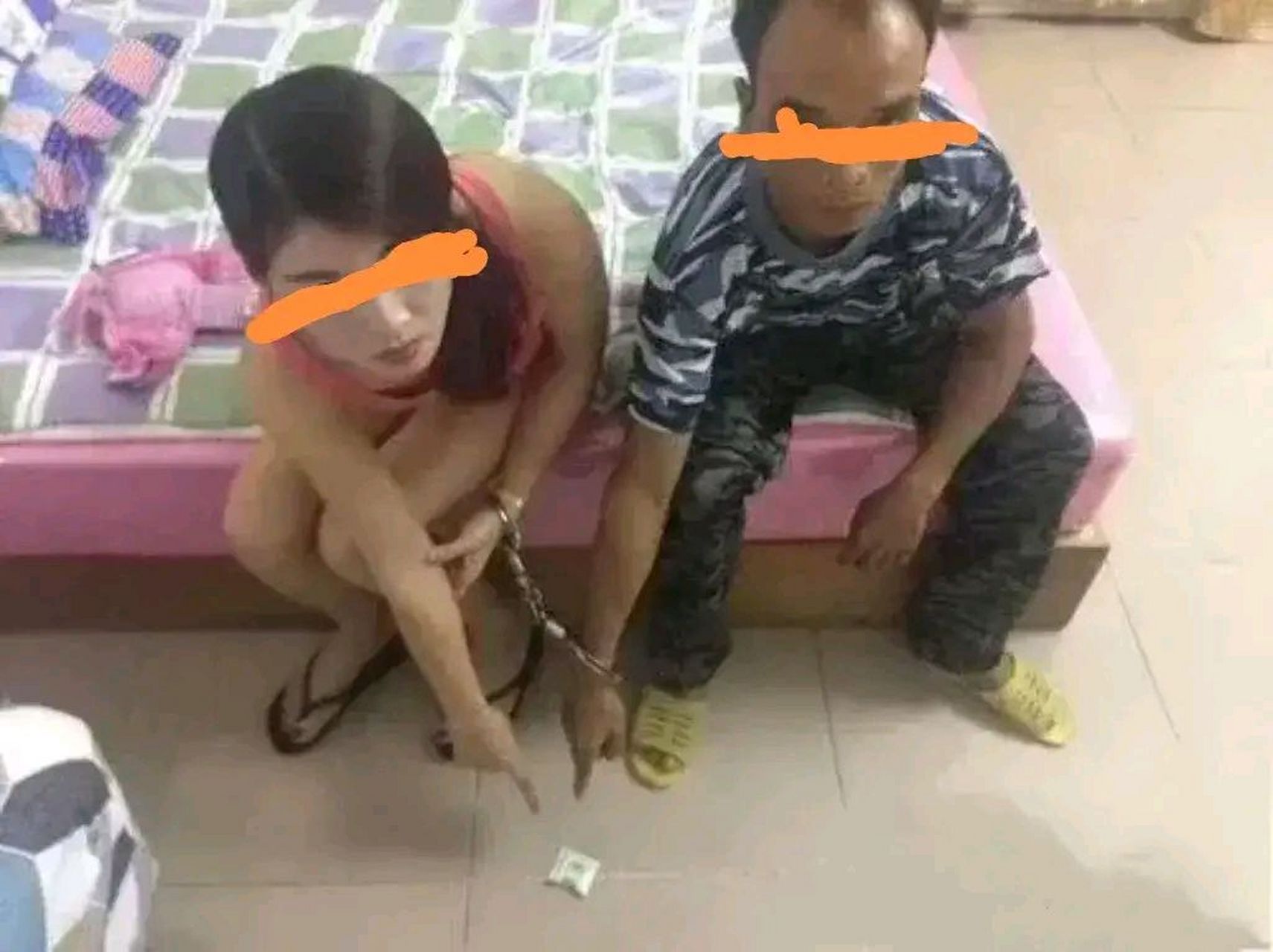 左边那名妇女,黑头发,披挂于肩,身穿粉色吊带衣,足蹬黑色人字拖.