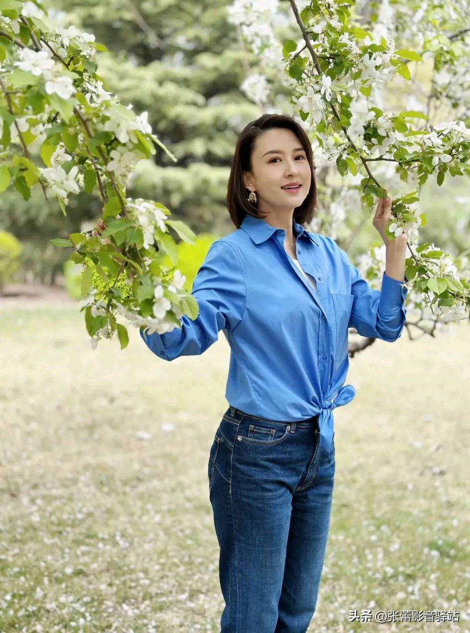 主持人张蕾icon游客照送上,穿蓝色衬衫山楂树下摆拍造型魅力十足,女人