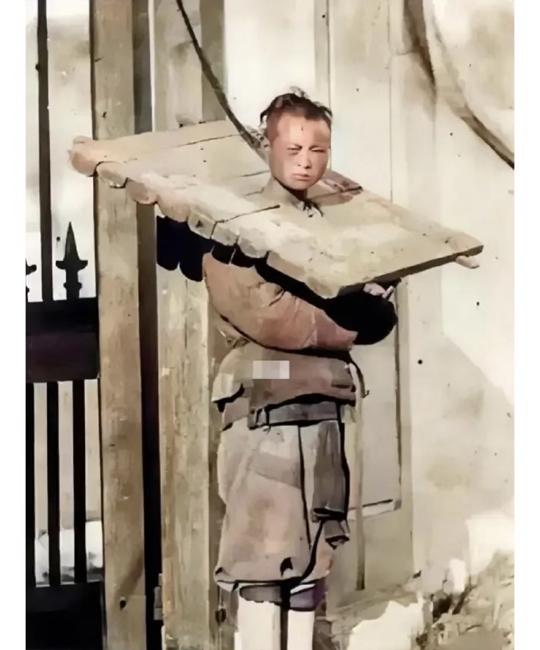 义和团一名男子被捕 他的脖子上套着沉重的枷锁 但是他的眼神很坚定