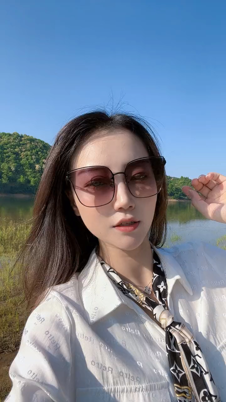 美女戴着深色大眼镜,在湖边自拍