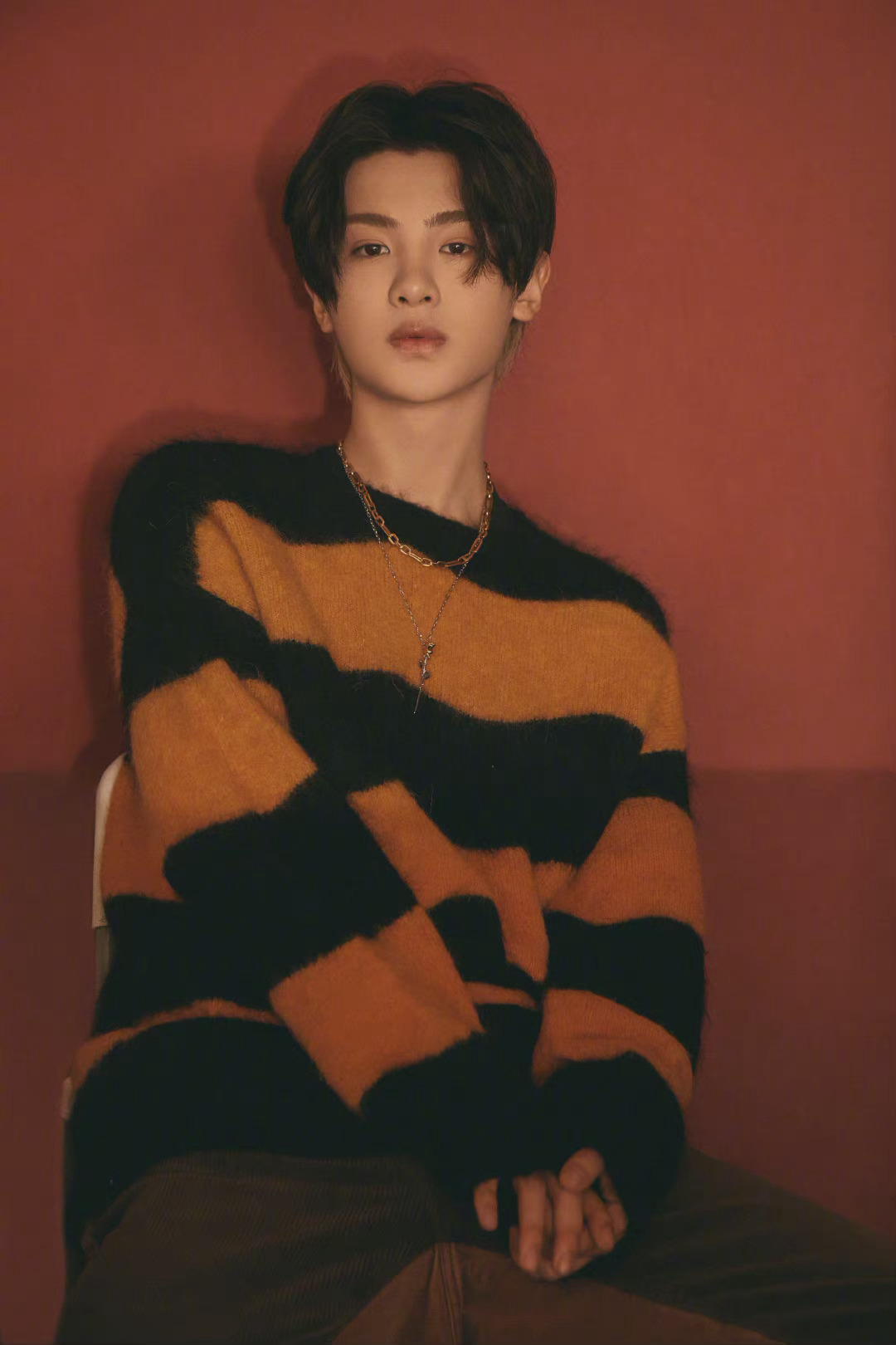 黄明昊身穿橙黑条纹针织衫,中分黑发尽显温柔潮男气质