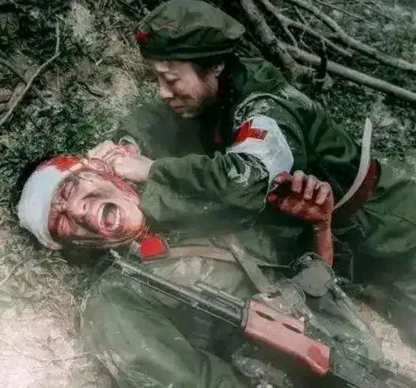1979年老山战役中,一名护士正在给受伤的战士包扎伤口.