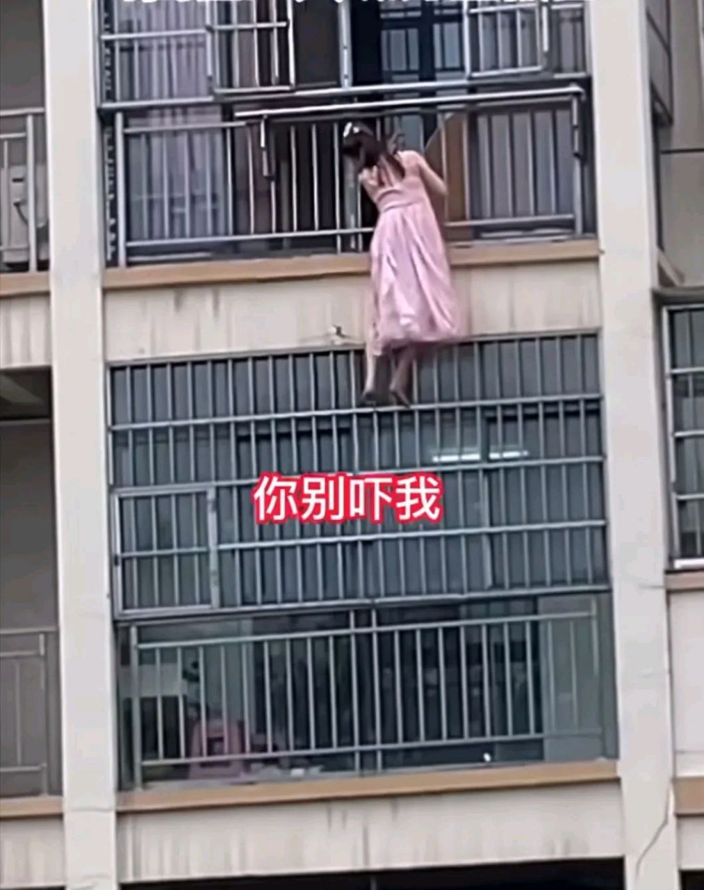 7月6日湖北黄石女子赤脚从高层阳台爬出防护网外面,对面住户以为她要