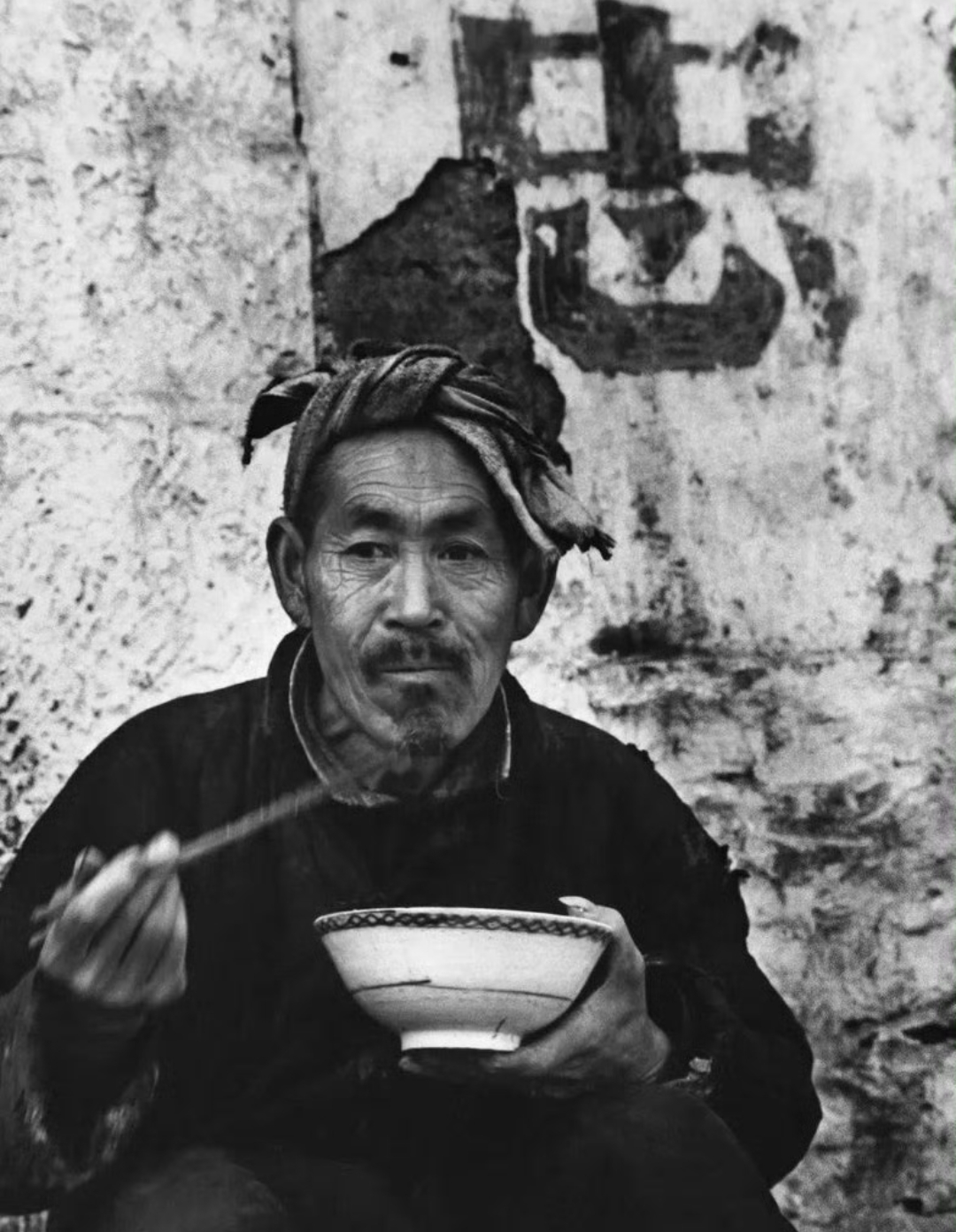 70年代,在河南某地,一位老农民正专注于用餐,他身着朴素的衣衫,面容