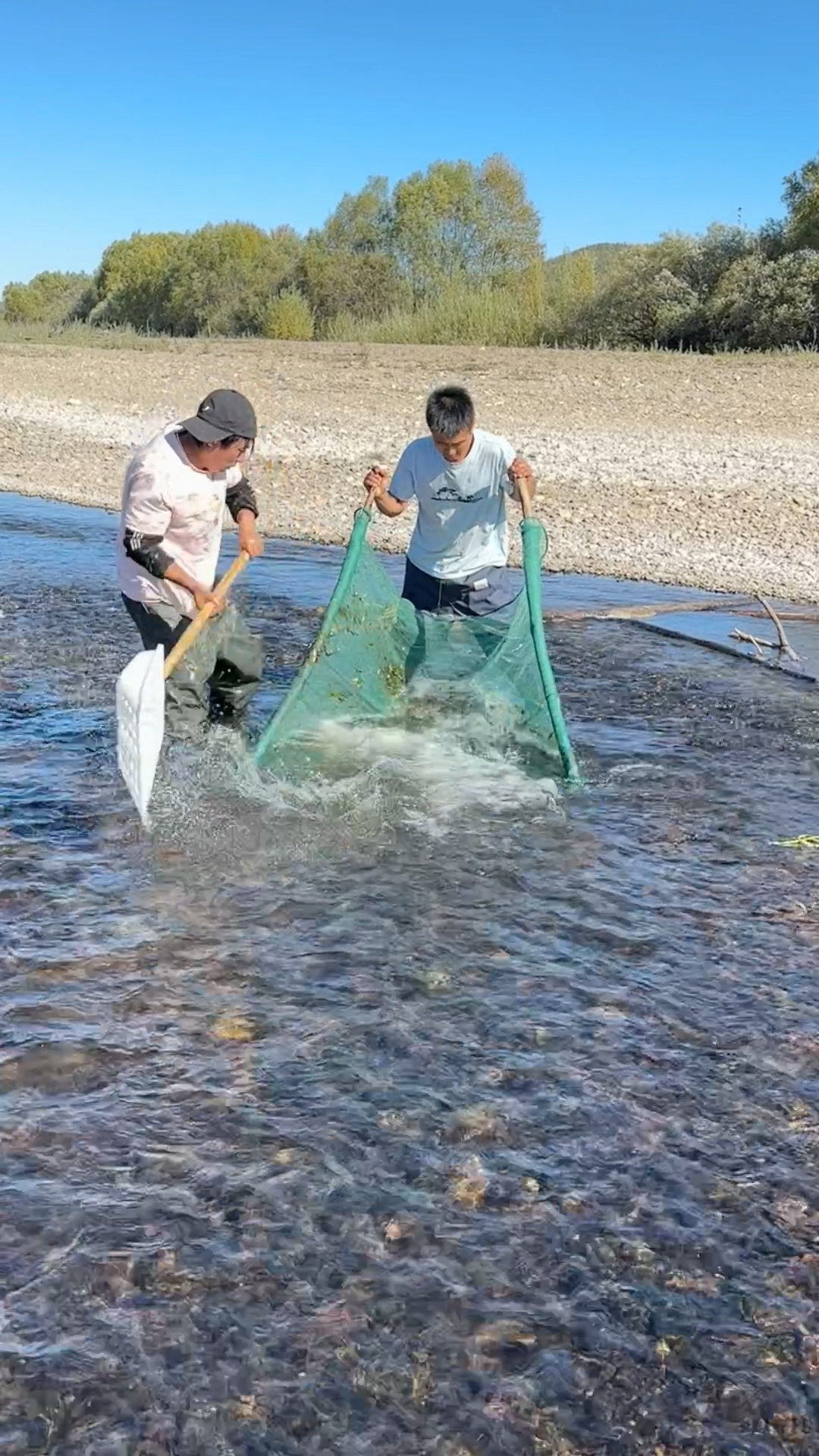 两个人合伙小河流里捞鱼