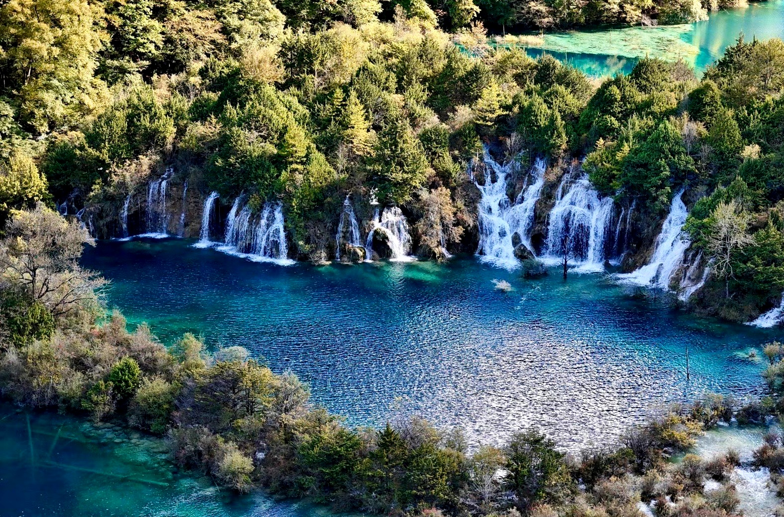 这是属于九寨沟的美景,一个个湖泊散落在大地上,蓝绿色的湖水清澈见底
