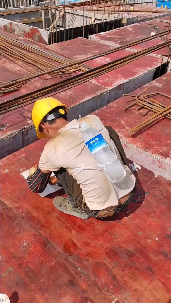 在工地炽热的阳光下,扎钢筋的工人汗流浃背